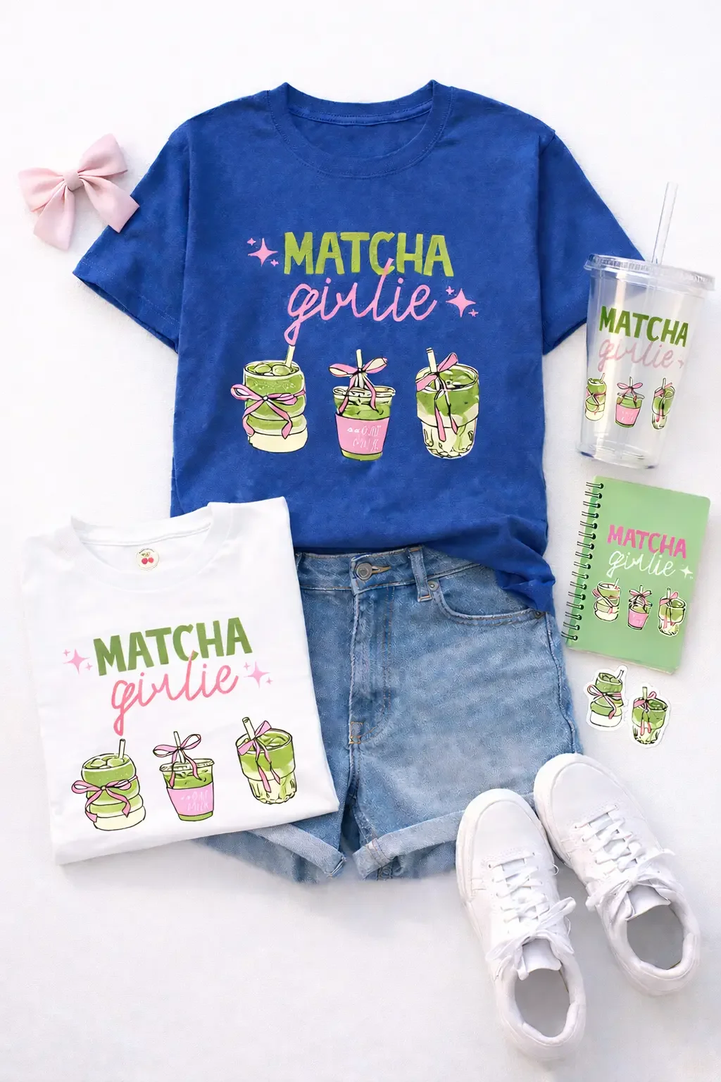 Flat lay of matcha girlie merchandise including blue and white graphic tees denim shorts white sneakers tumbler notebook stickers and a hair bow.