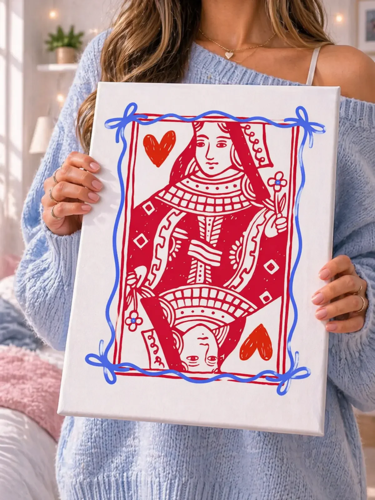 Model holding a red playing card canvas print in a bright bedroom filled with pink bedding and preppy room decor accessories.