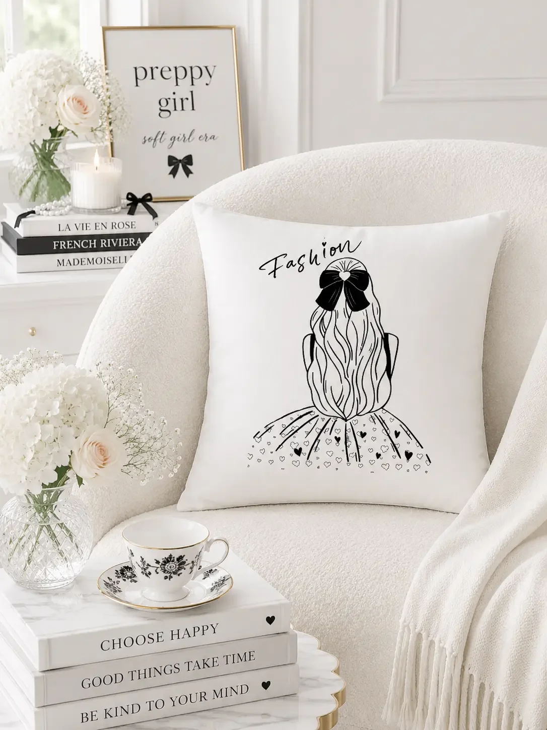 A square white throw cushion with a black line art graphic of a girl wearing a black hair bow resting on a cream boucle armchair.