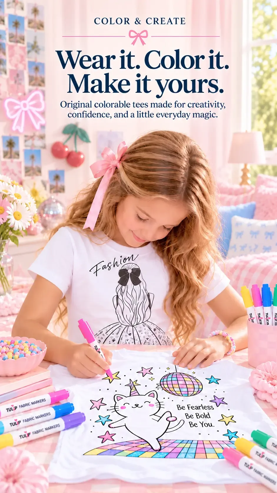 • A young girl coloring a white cat and disco ball graphic t-shirt with Tulip fabric markers in a pink bedroom.