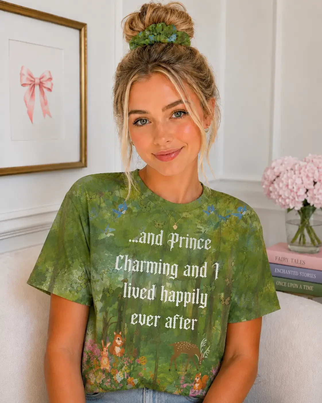 Smiling blonde woman with a messy bun and green scrunchie wearing a green forest scene crewneck fairy tale graphic shirt.