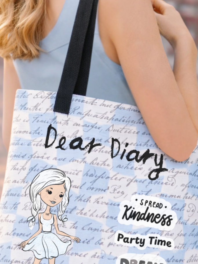 Close-up of a white tote bag with a script writing print pattern, a cartoon illustration, and text reading Dear Diary.