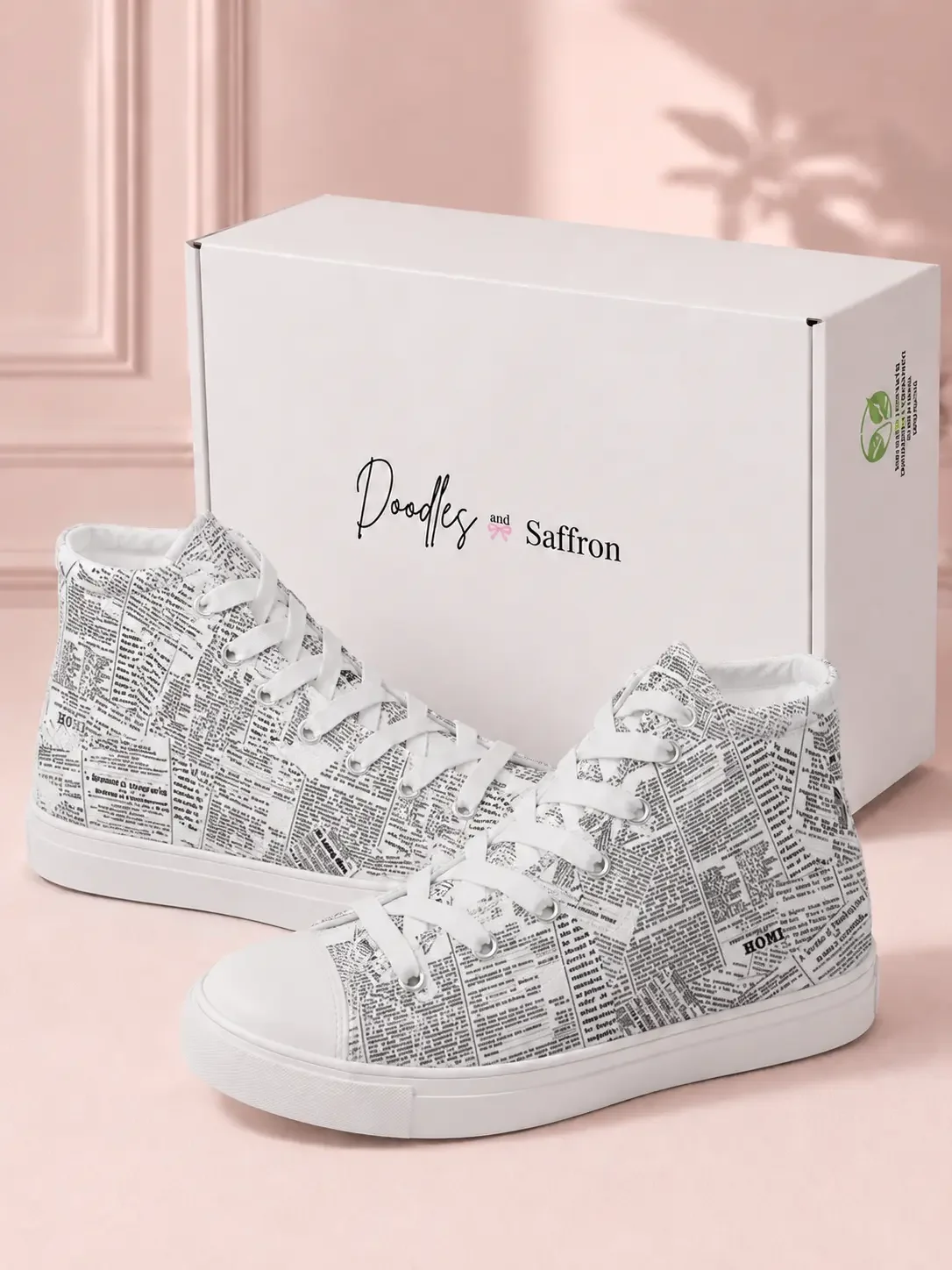 A pair of white vintage newspaper print high-top sneakers displayed in front of a white Doodles and Saffron shoebox.