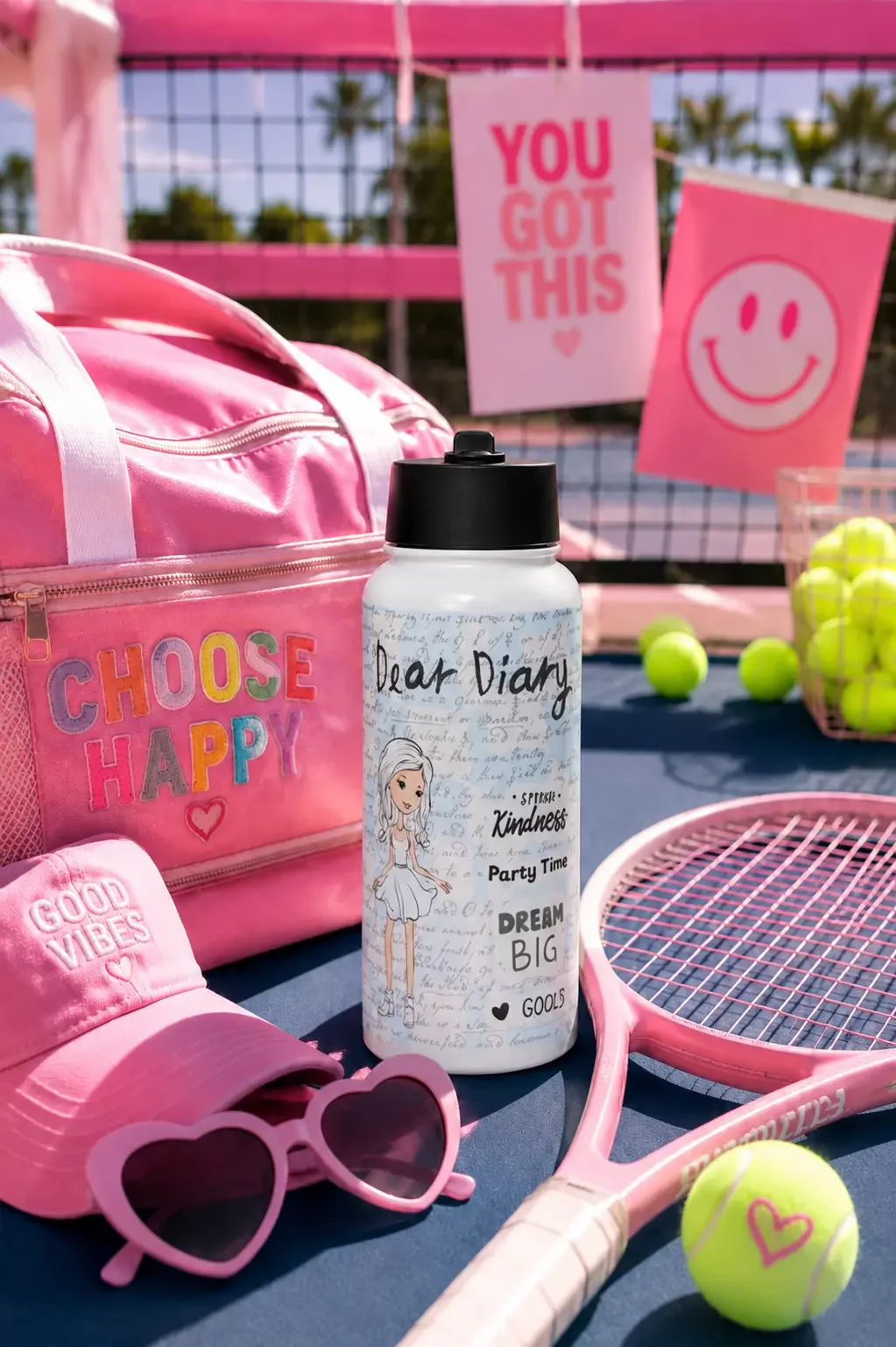 A handwritten journal design water bottle next to a pink sports duffel bag, tennis racket, and heart sunglasses.