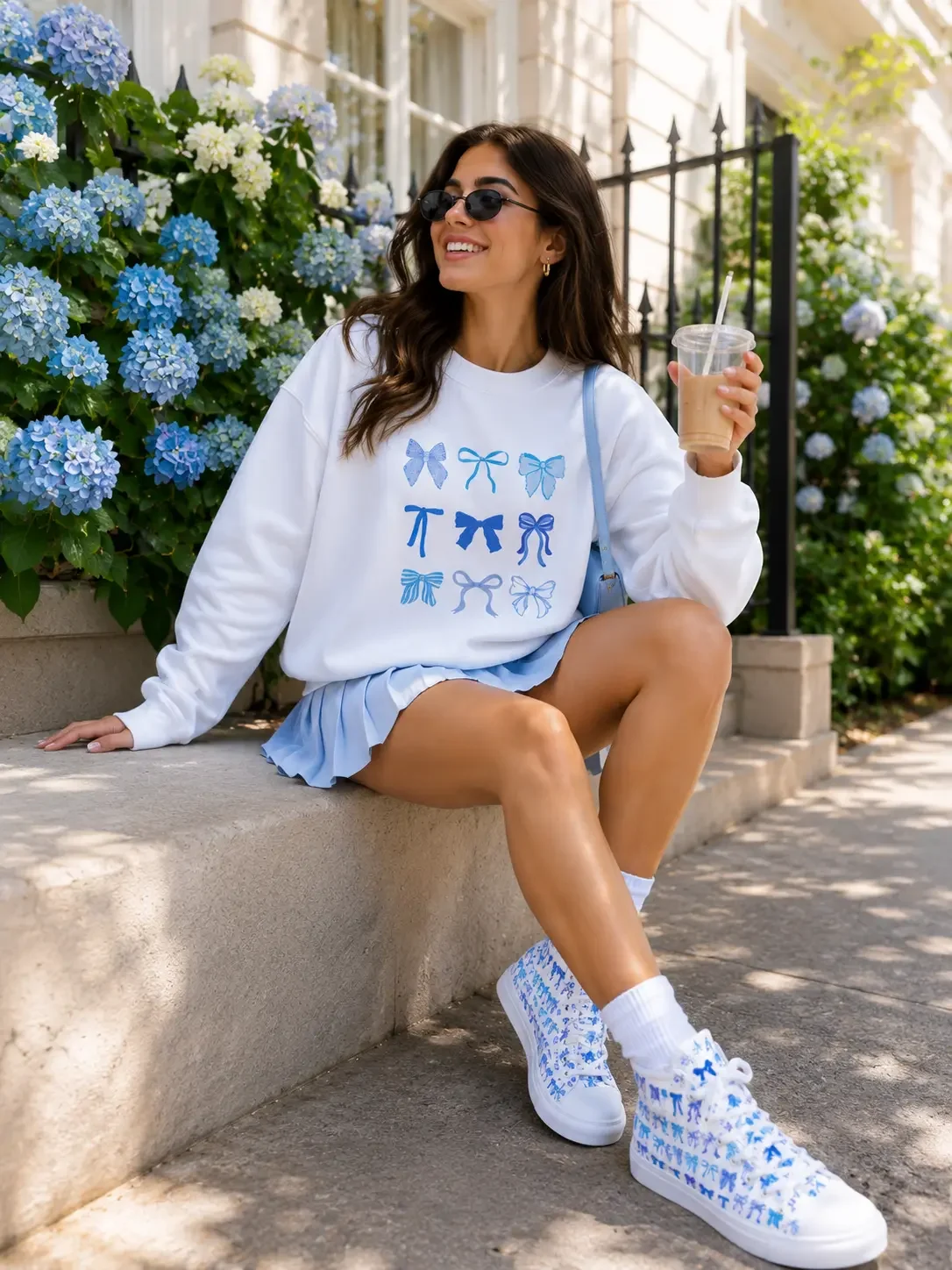 White crewneck sweatshirt featuring a graphic pattern grid of nine distinct light blue ribbon bows.