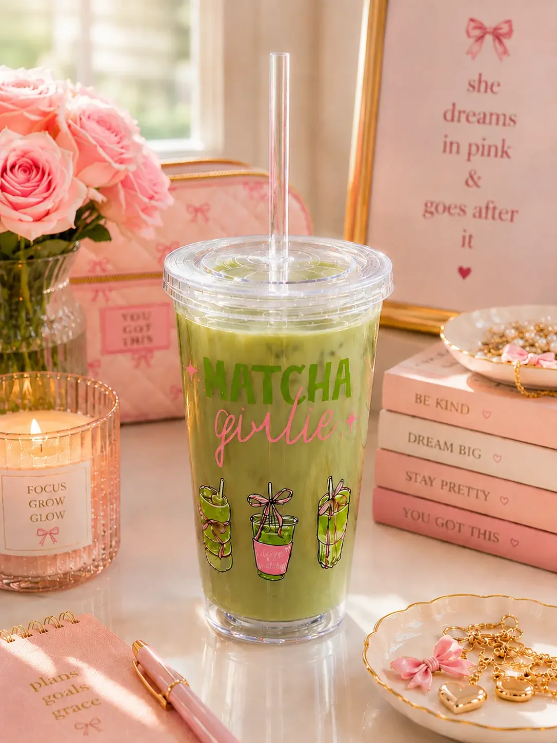 Preppy "Matcha Girlie" tumbler cup filled with green matcha, sitting on a pink aesthetic desk with flowers and candles.