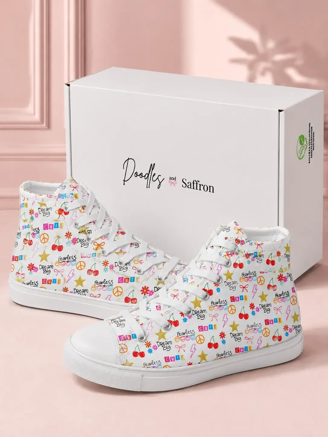 A pair of white doodle graphic print high-top sneakers displayed in front of a white Doodles and Saffron shoebox.
