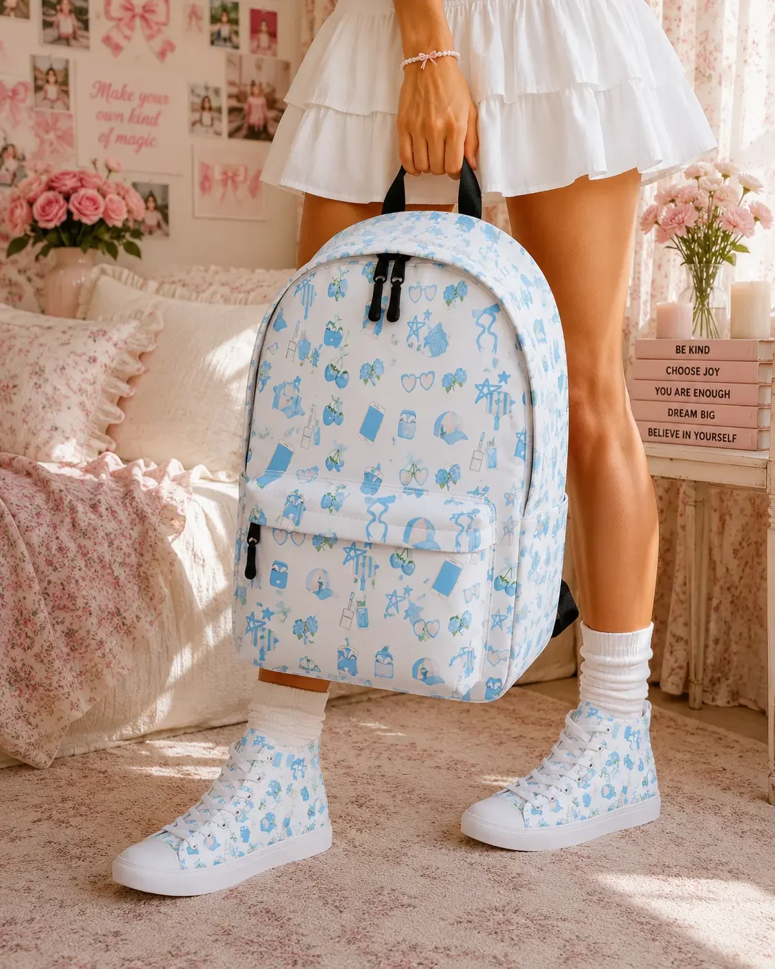 Young woman wearing a white skirt and matching blue icon sneakers holds a blue preppy icon pattern backpack in a bedroom.