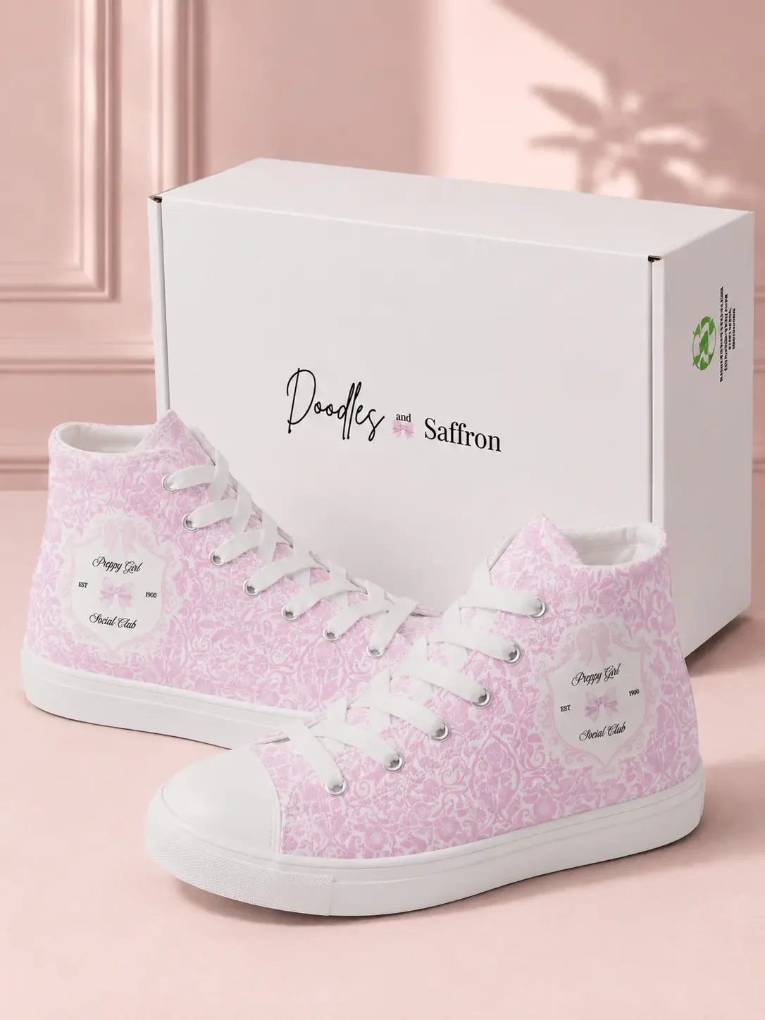Pair of pink toile print high-top canvas sneakers standing in front of a white Doodles and Saffron branded shipping box.