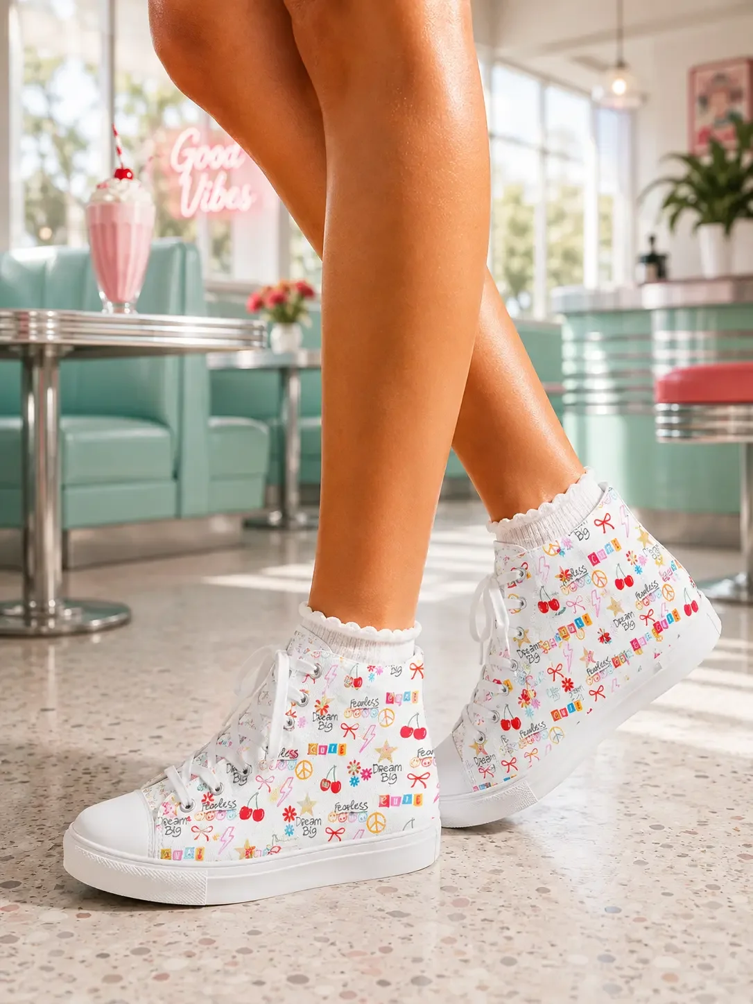 Close-up of a person standing in a diner wearing white doodle graphic print high-top canvas sneakers and ruffle socks.
