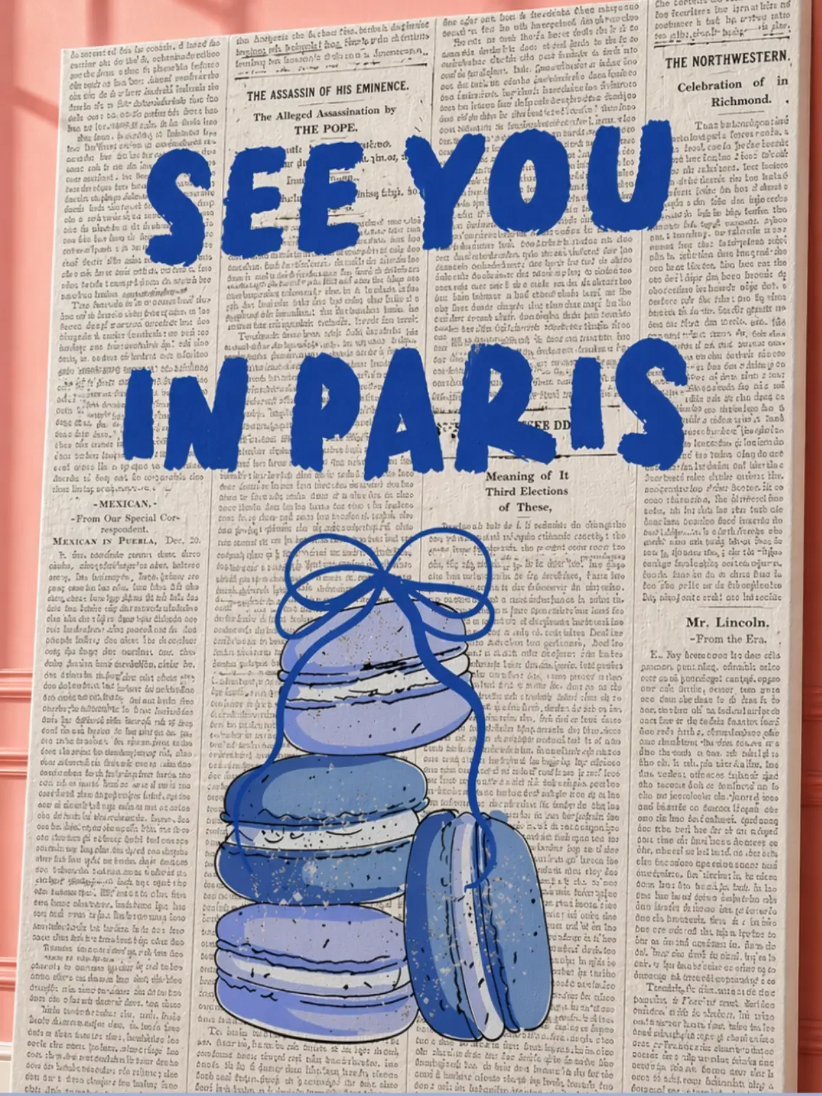 Close-up mockup of the Doodles and Saffron See You In Paris canvas print showcasing vintage text and macaron textures near a pink wall.