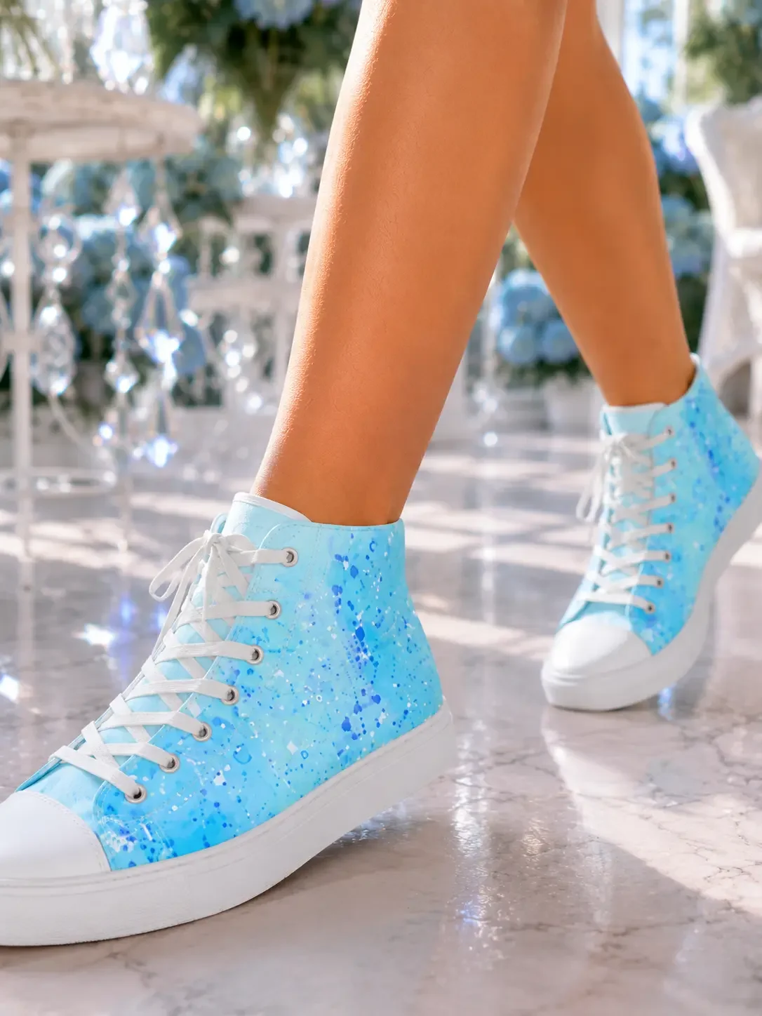 Close-up of a person walking in light blue paint splatter print high-top canvas sneakers inside a bright greenhouse garden.