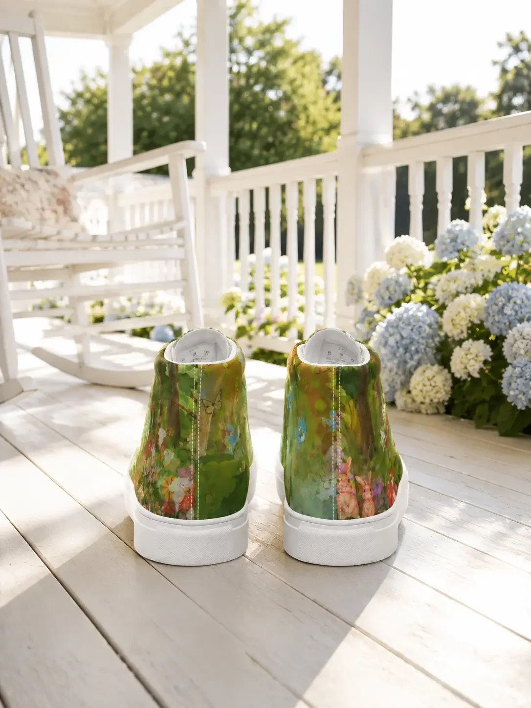 Back heel view of forest woodland print high-top canvas sneakers displayed on a sunny porch with hydrangeas and a white rocking chair.