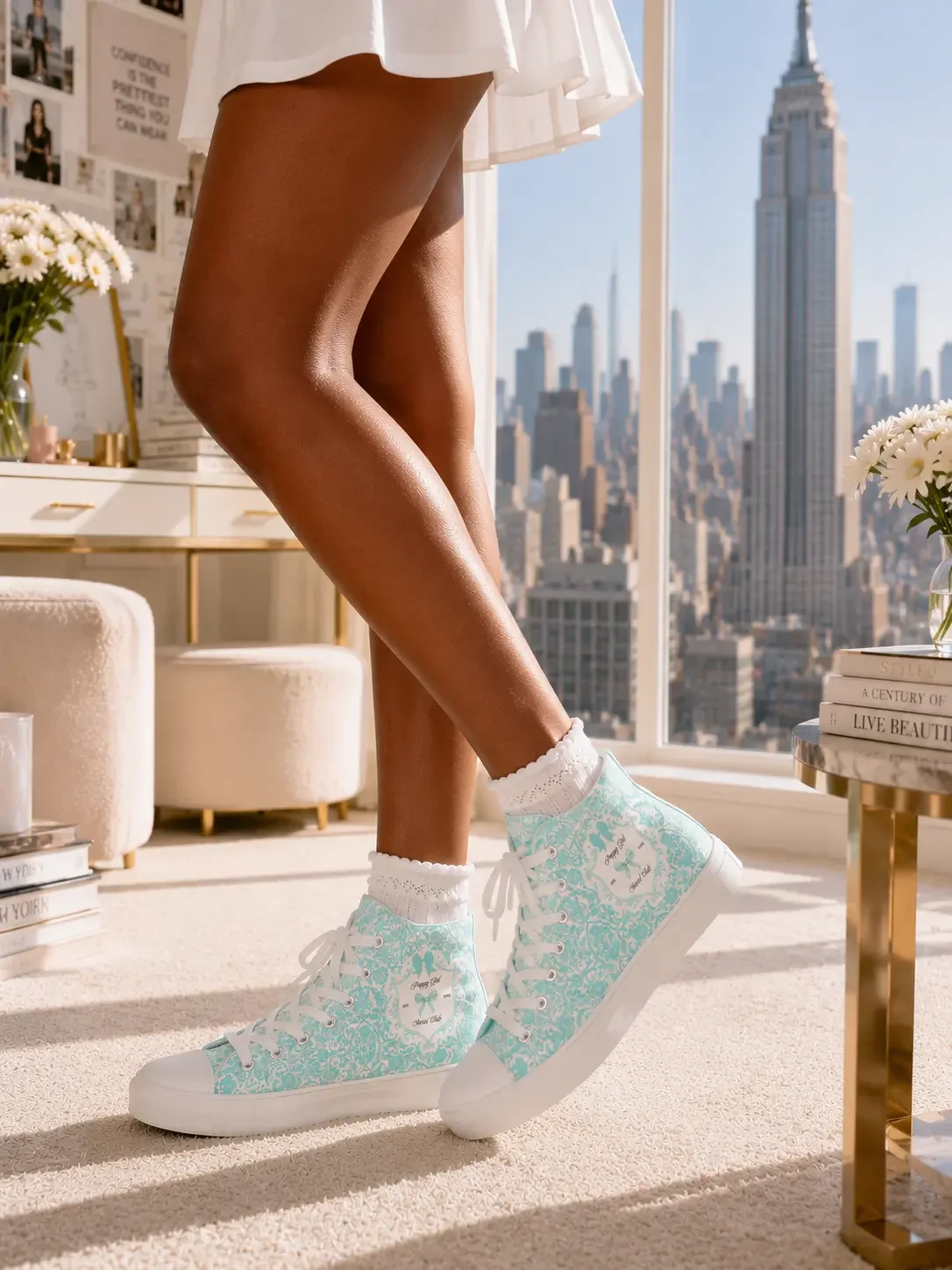 Woman smiling while walking in a high-rise office wearing a mint green lace graphic t-shirt, matching high-top sneakers, and white pleated skirt.