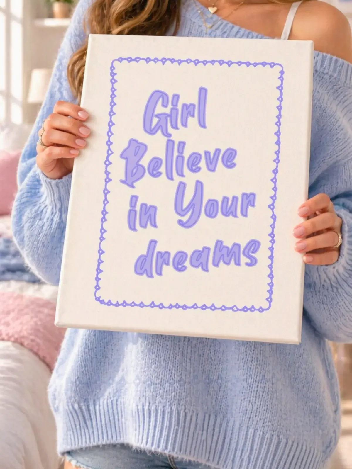 A girl in a blue knit sweater holds the Doodles and Saffron canvas print featuring purple quote typography inside a wavy border.