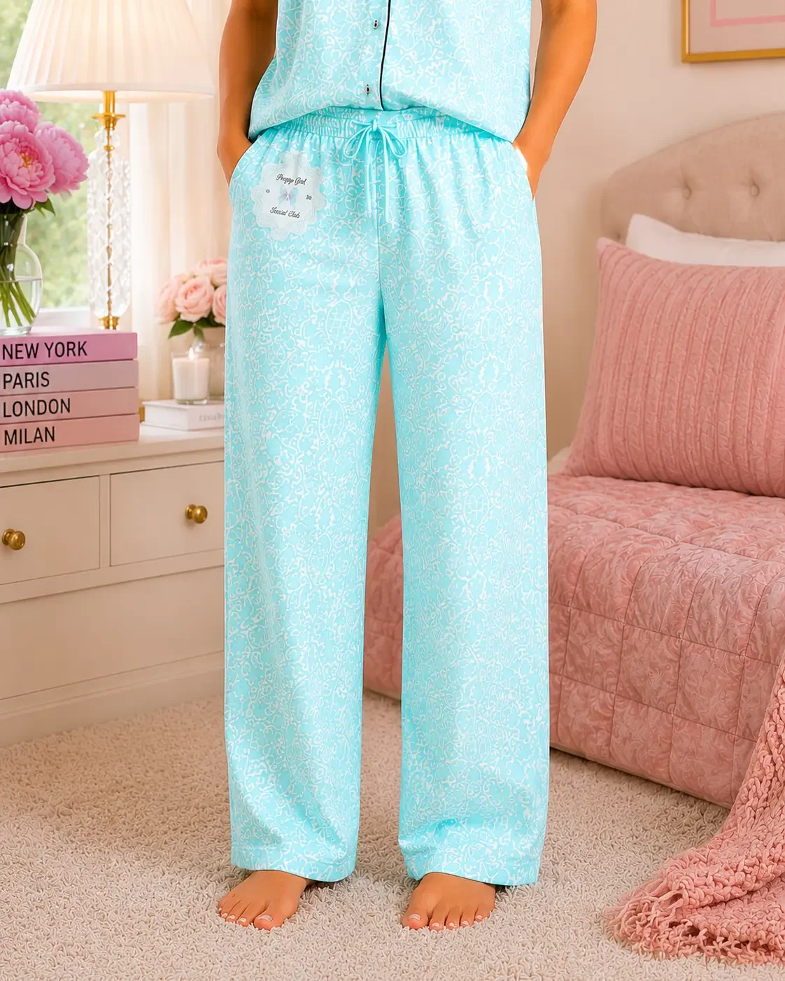 Close-up of blue floral wide-leg pajama pants featuring an elastic drawstring waist and a Preppy Girl Social Club badge.