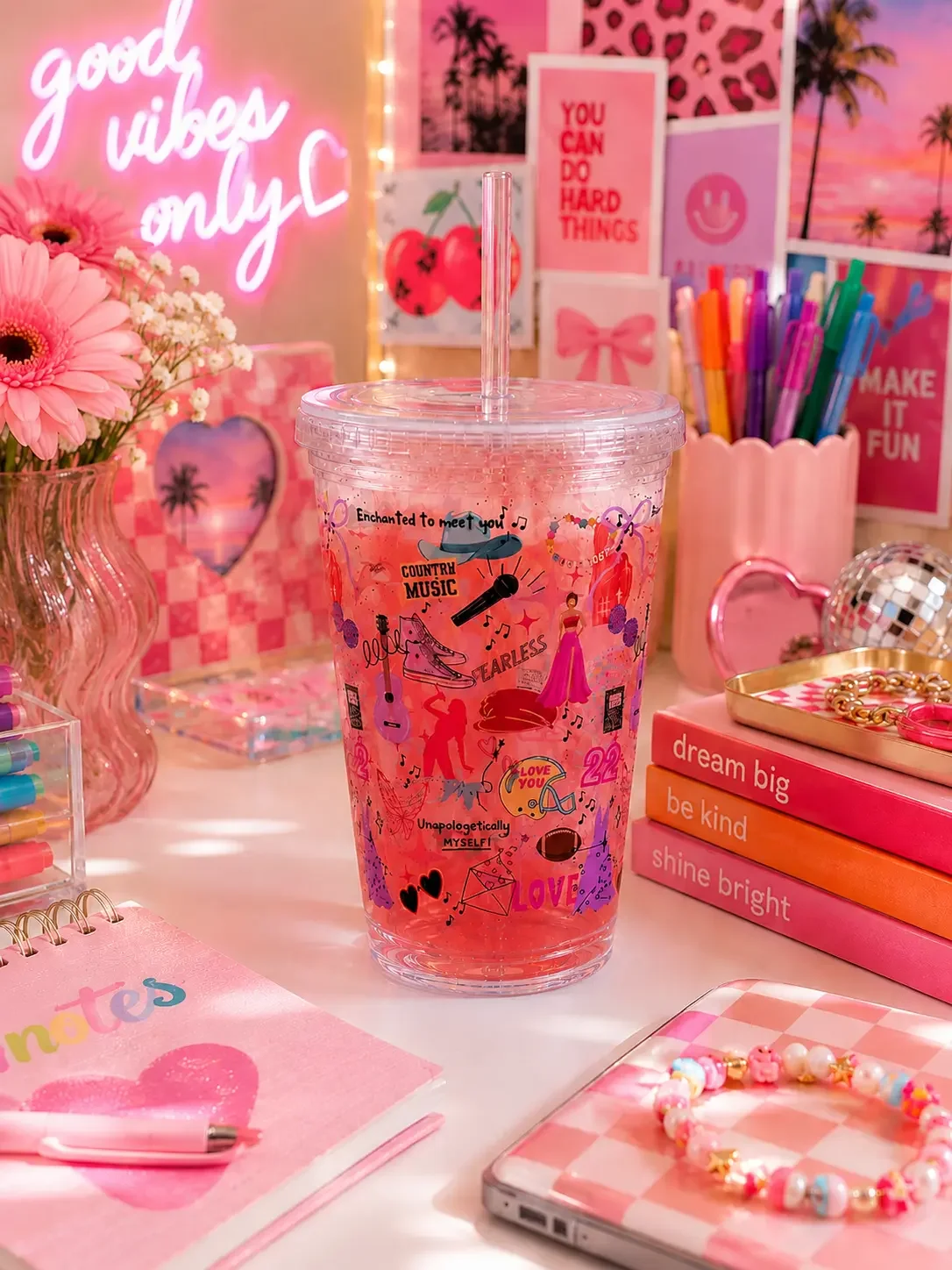 A preppy country music pop star doodle tumbler cup filled with a pink iced drink on an aesthetic neon-lit desk setup.