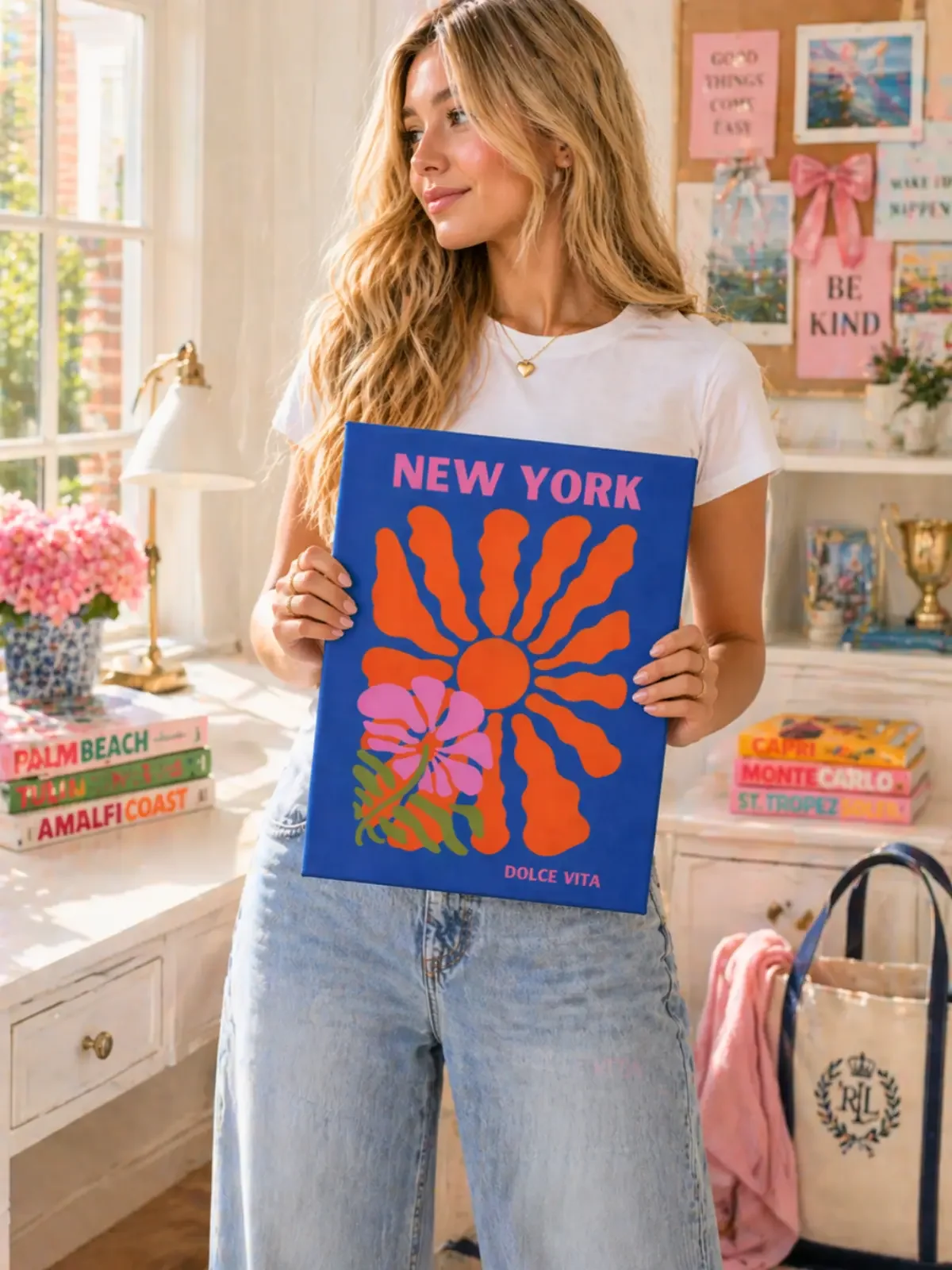 A smiling girl holds a New York Dolce Vita canvas art print by Doodles and Saffron standing inside a decorated preppy room.