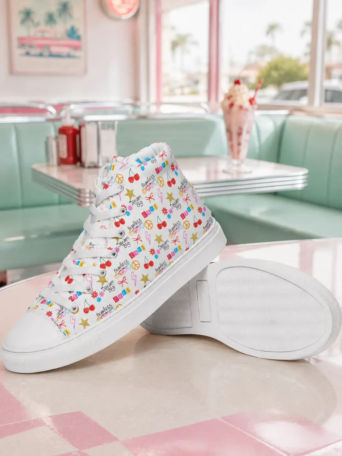White doodle print high-top canvas sneakers displayed on a retro diner table with a pink milkshake blurred in the background.