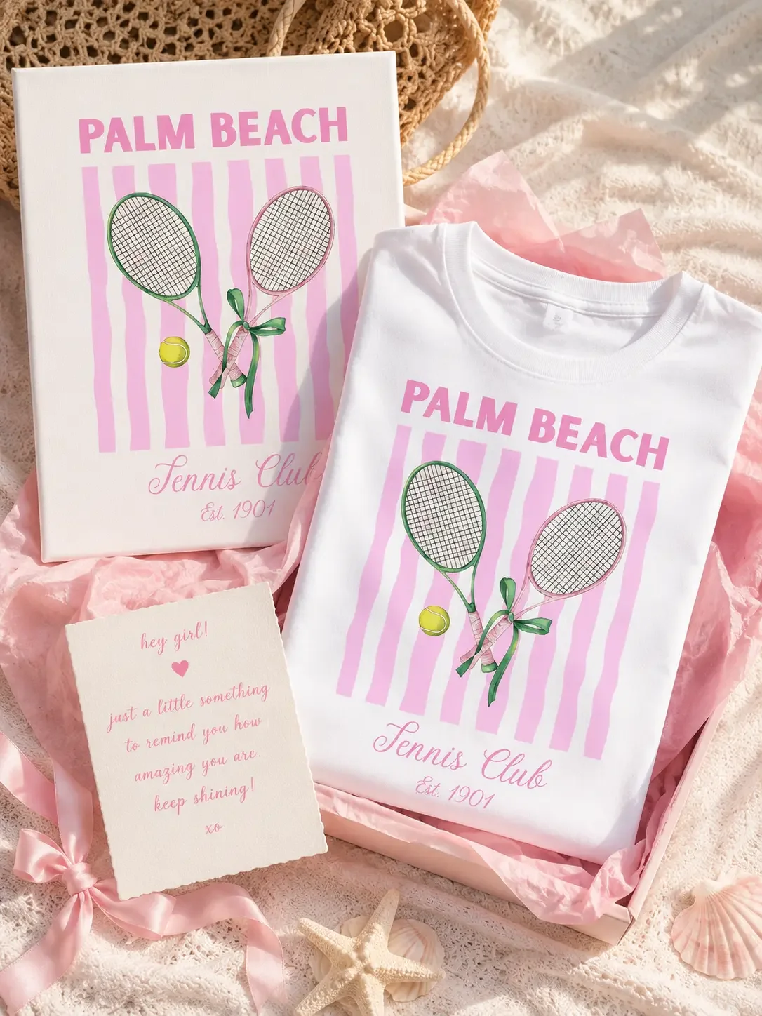 Open pink gift box containing a folded white Palm Beach Tennis Club t-shirt, matching wall art canvas, and a pink motivational note card. (Copy)
