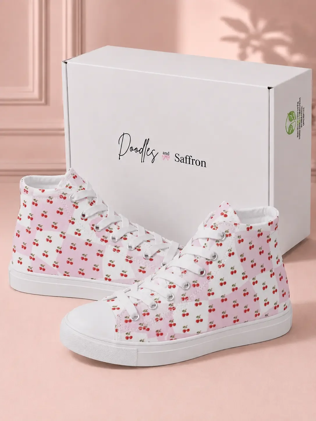 Pair of pink checkered high-top sneakers with a cherry print design sitting in front of a white retail packaging box.