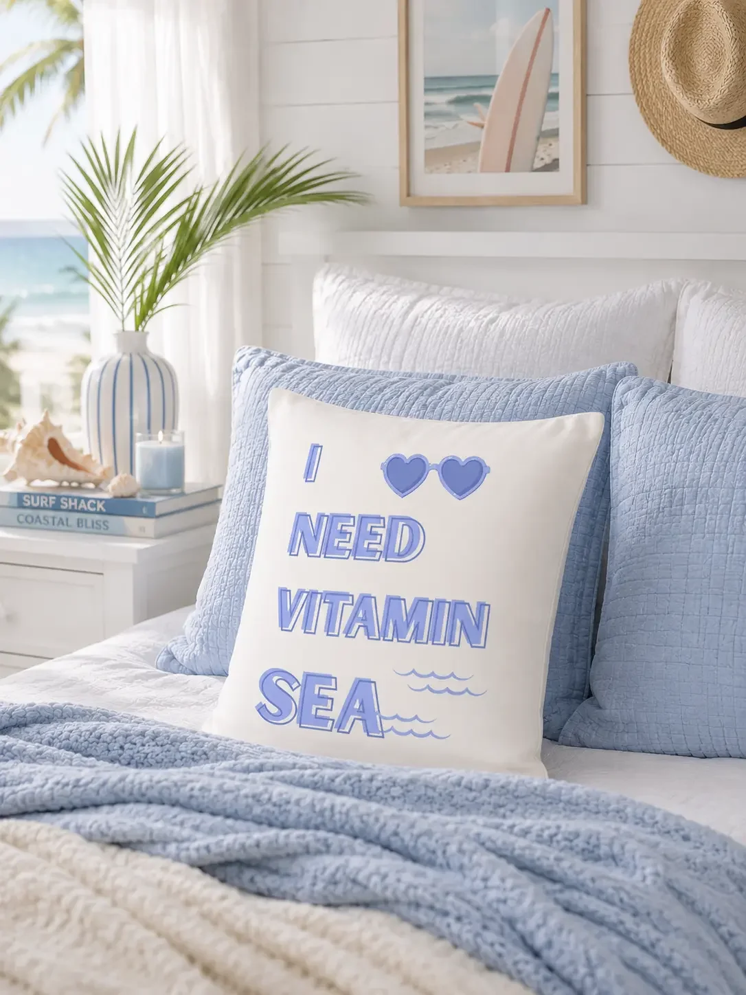 The Doodles and Saffron Vitamin Sea throw pillow styled on a coastal bed setup with light blue pillows and a palm leaf vase.