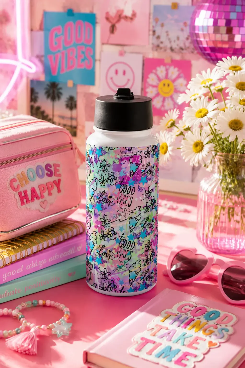 A white insulated water bottle with colorful graffiti doodles standing on a pink desk among preppy desk accessories.
