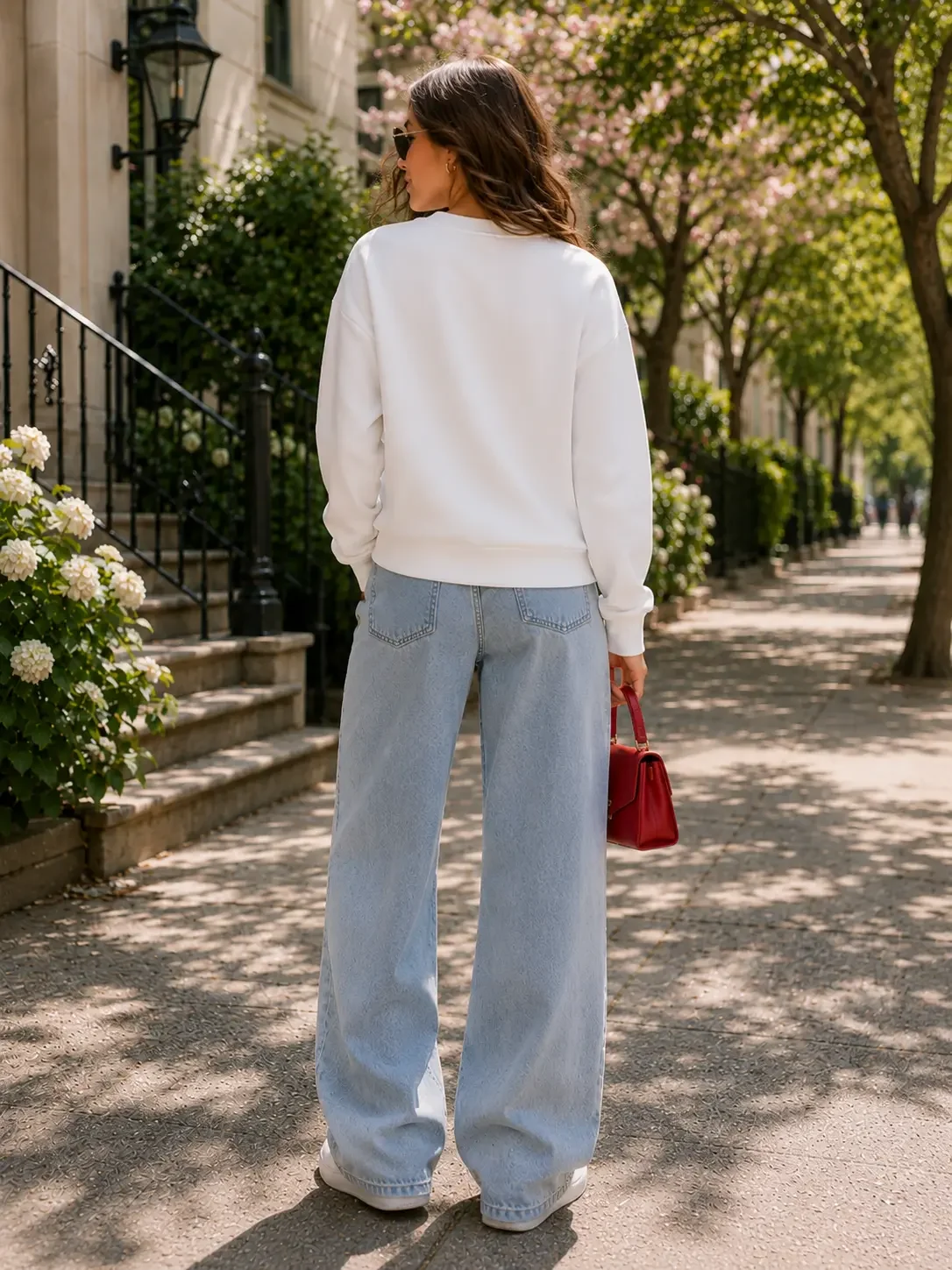 Back view of a relaxed-fit white cotton crewneck sweatshirt styled casually with loose light-wash denim jeans.
