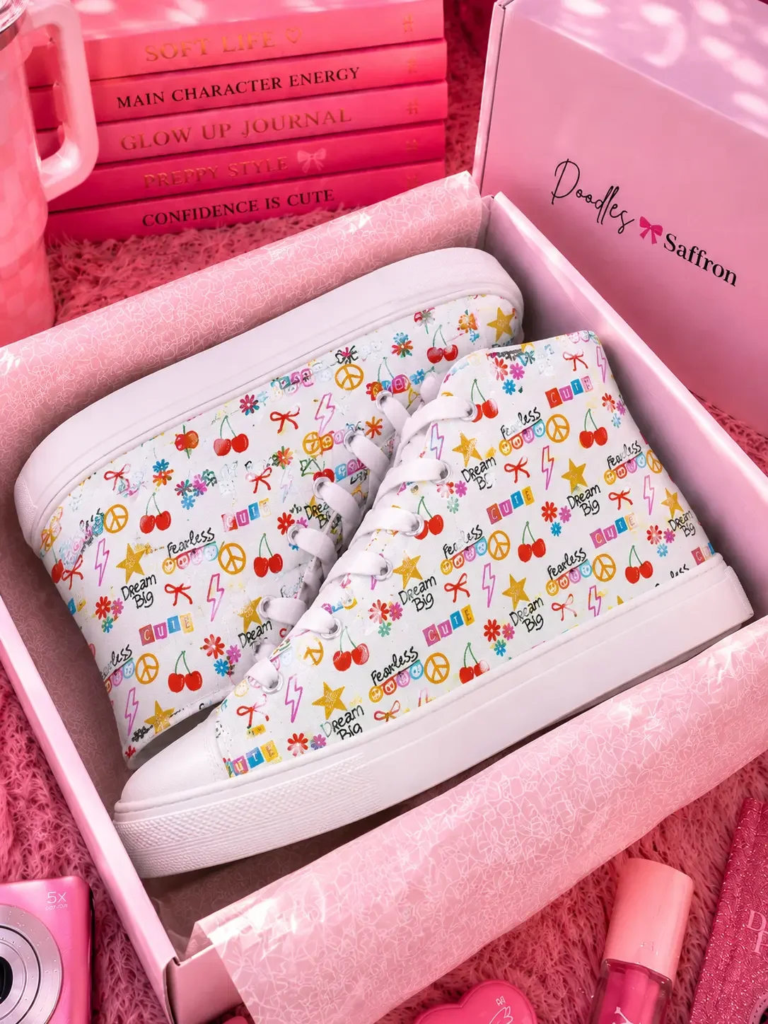 A pair of white doodle print high-top sneakers packed neatly inside an open white Doodles and Saffron shoebox.