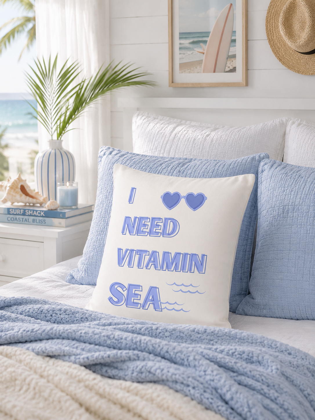 The Doodles and Saffron Vitamin Sea throw pillow styled on a coastal bed setup with light blue pillows and a palm leaf vase.