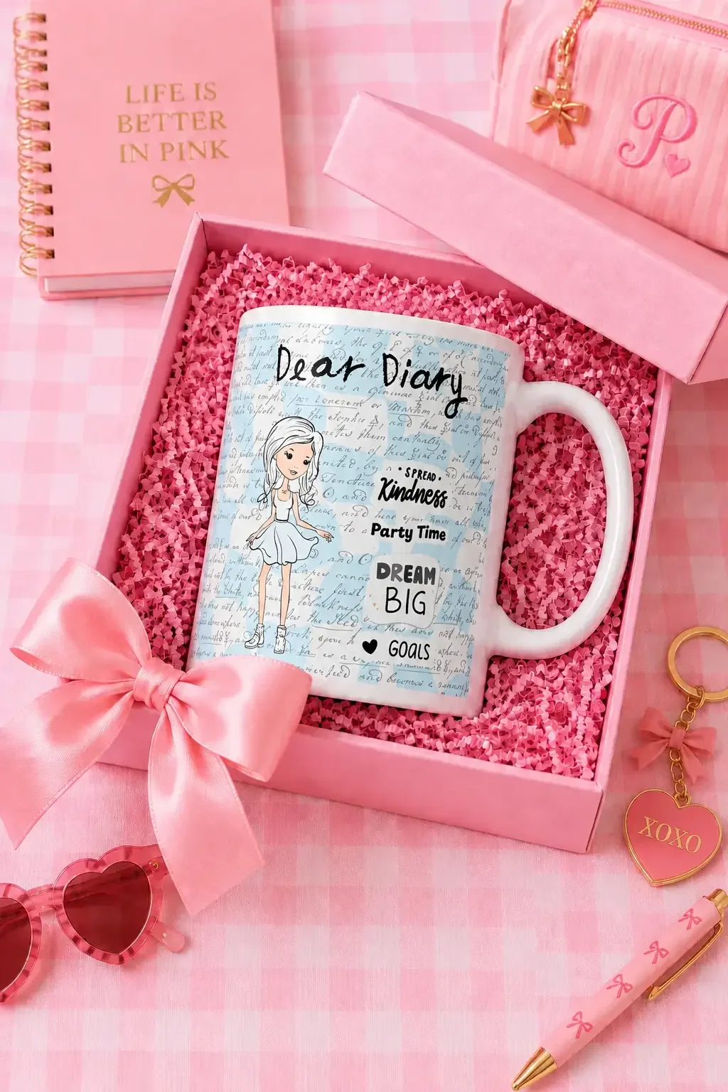 White Dear Diary mug inside an opened pink gift box with a bow, surrounded by a pink notebook and stationary.