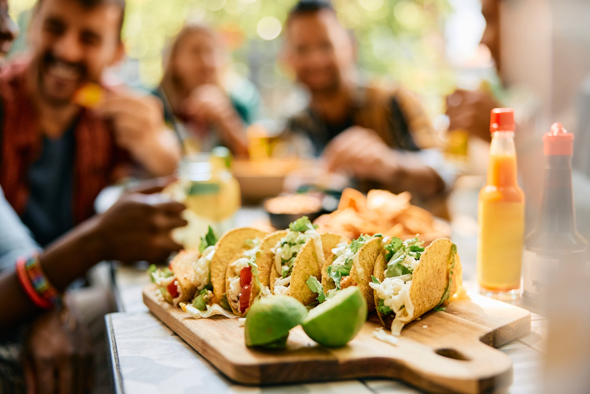 group of people eating tacos with the taco display on the table being the main focus