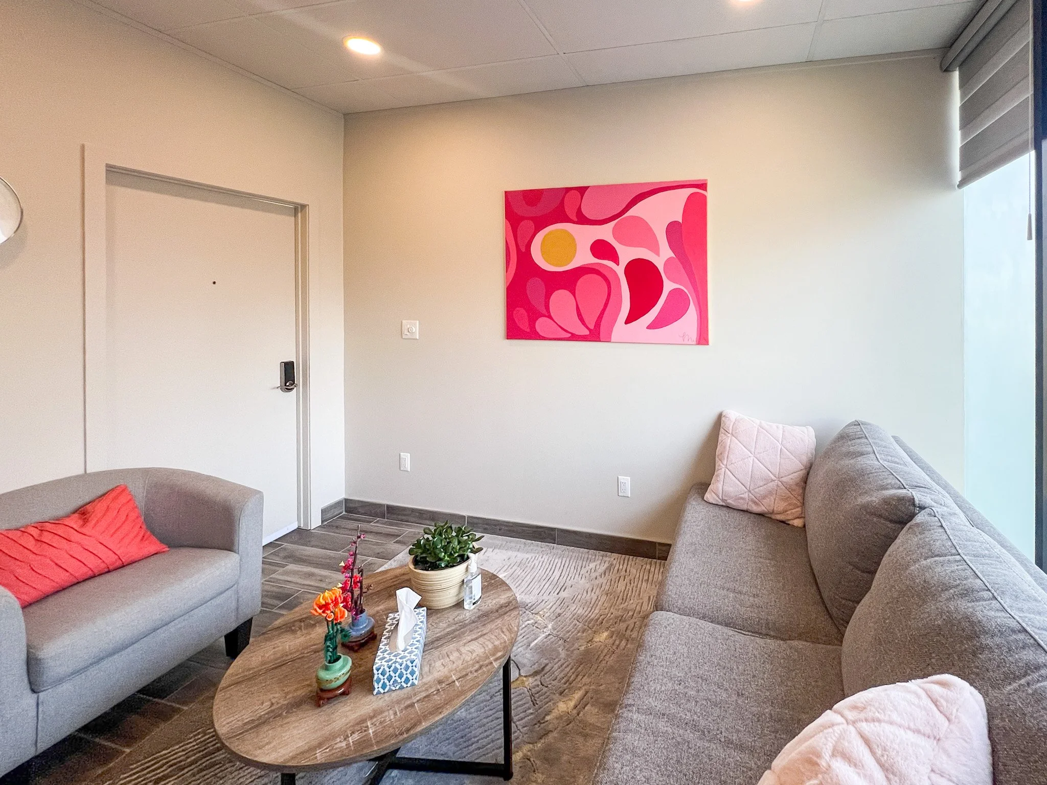 therapist office space with chair, wooden coffee table, cozy couch and bright artwork