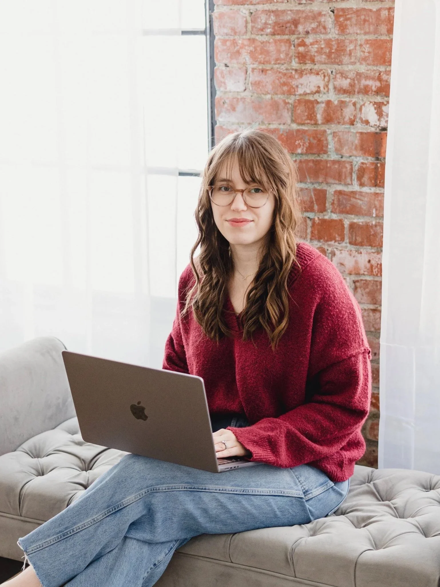Eating disorder dietitian Alexis Culhane smiling softly, seated with her laptop in a red sweater