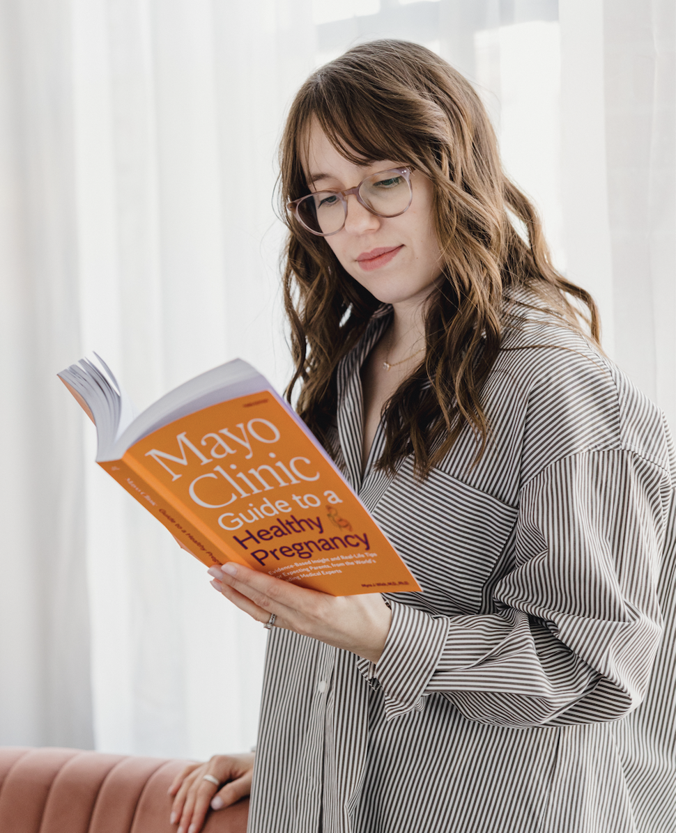 Dietitian specializing in perinatal nutrition reading Mayo Clinic's guide to healthy pregnancy, encouraging women to join 1:1 counseling program for women approaching the fourth trimester