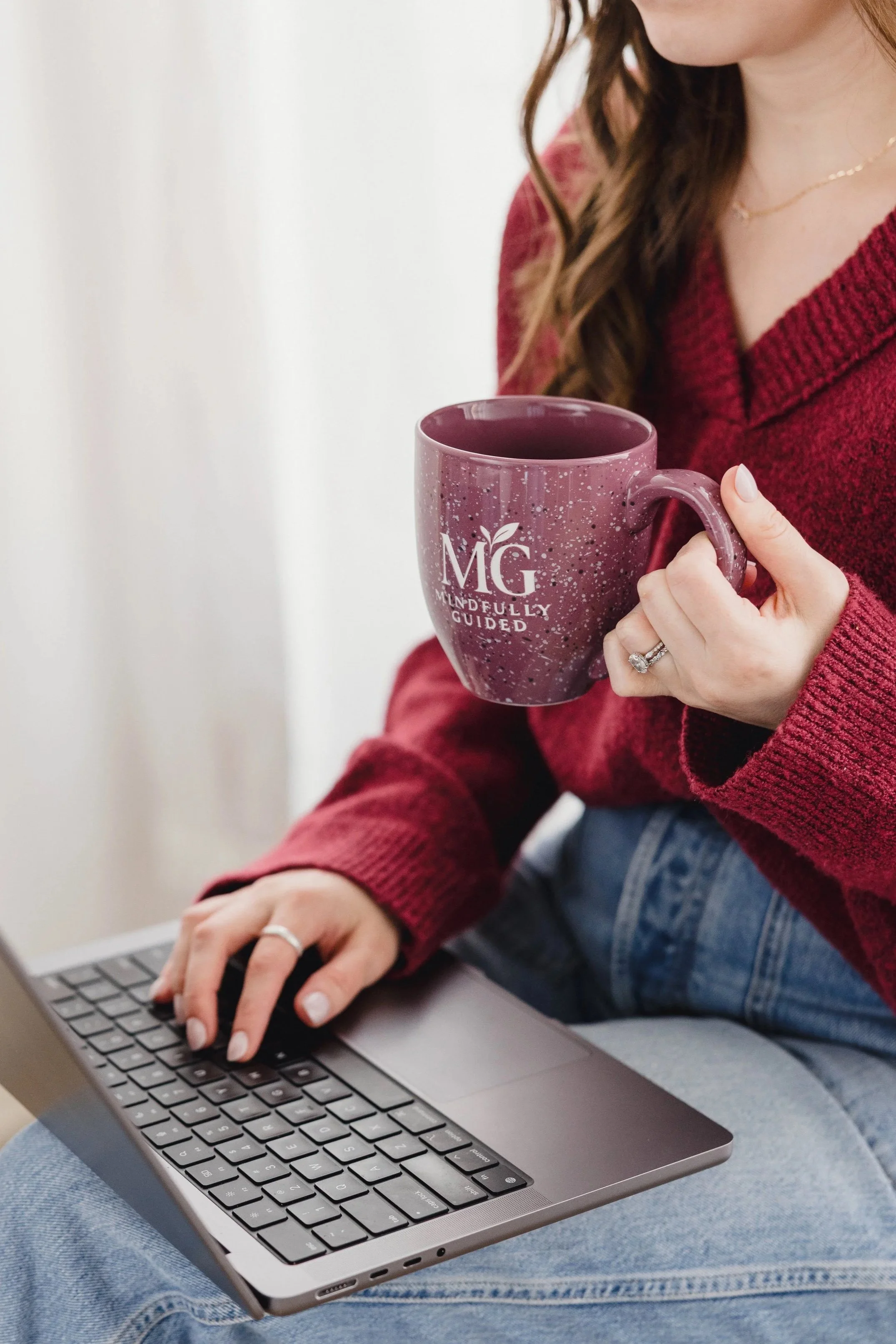 Registered dietitian Alexis Culhane sipping coffee while working on her laptop, offering weight-neutral nutrition support from home.