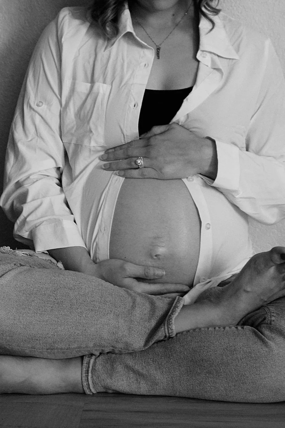 Pregnant person cradling their belly with both hands, representing prenatal nutrition support