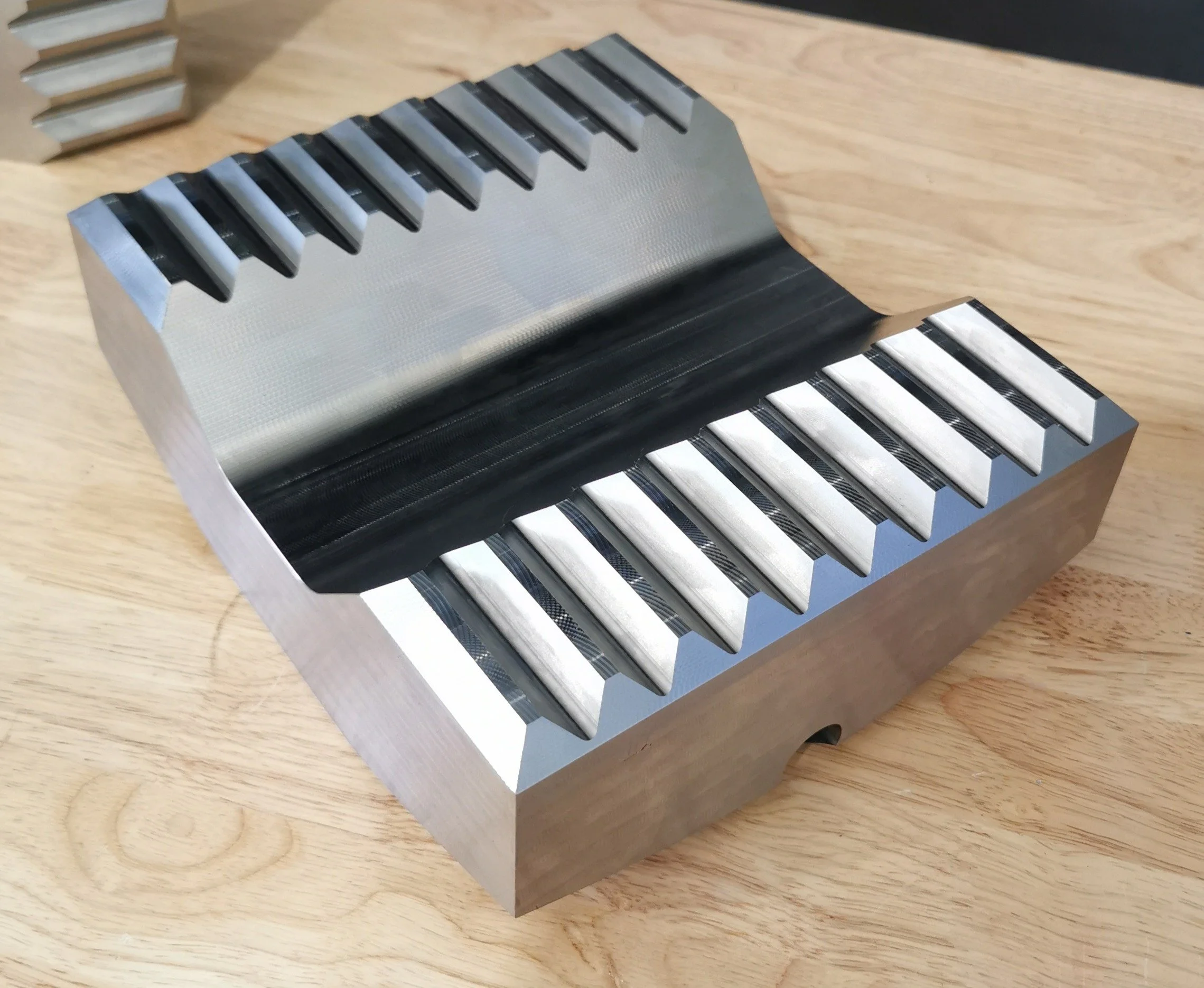 A metal cast iron mold with two rows of rectangular slots, placed on a wooden surface, used for making chocolates or candies.