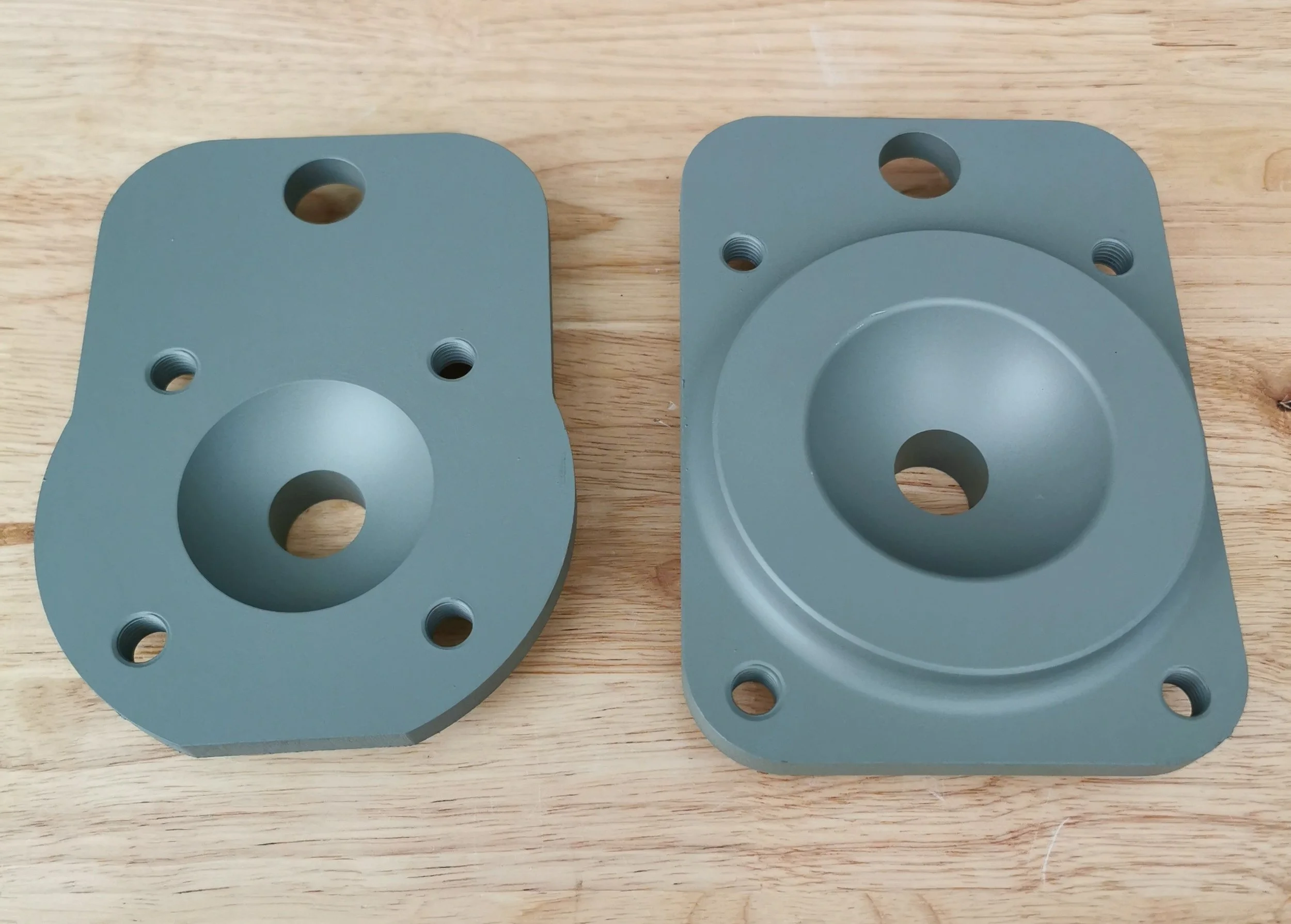 Two blue metal mounting brackets with holes on a wooden surface.