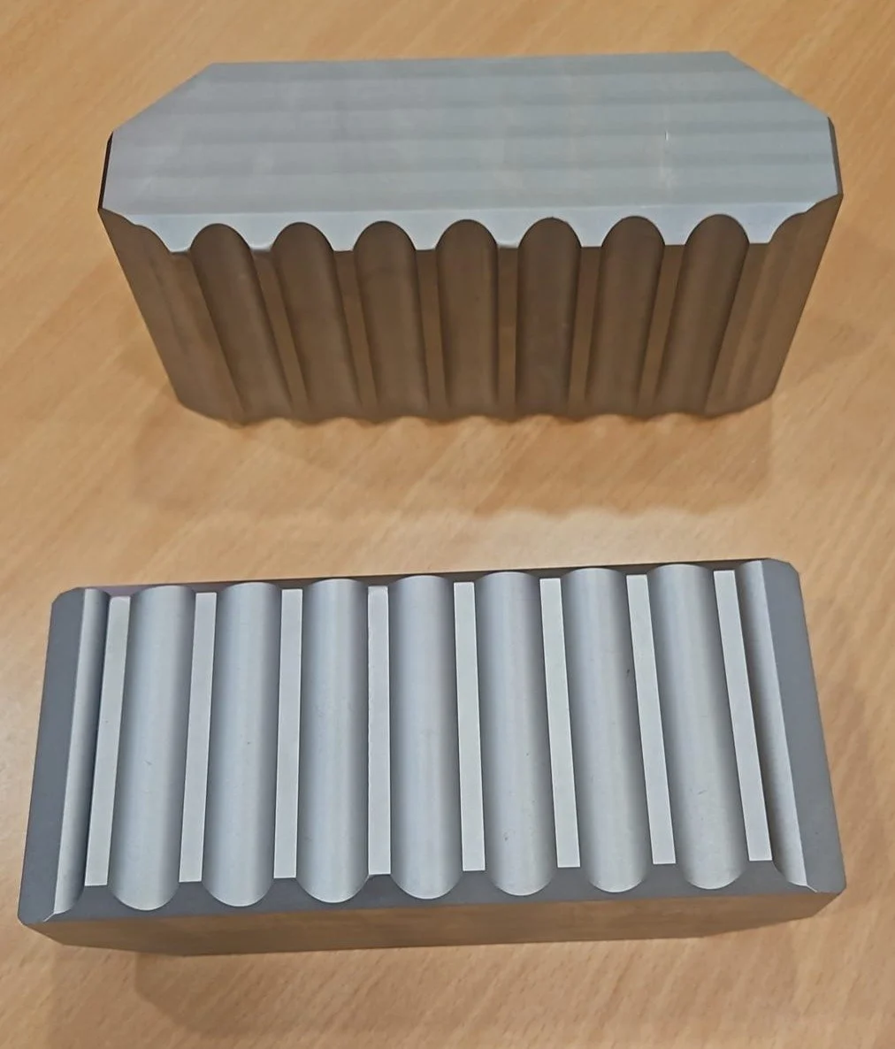 Two metallic cake molds with fluted and ridged patterns, placed on a wooden surface.