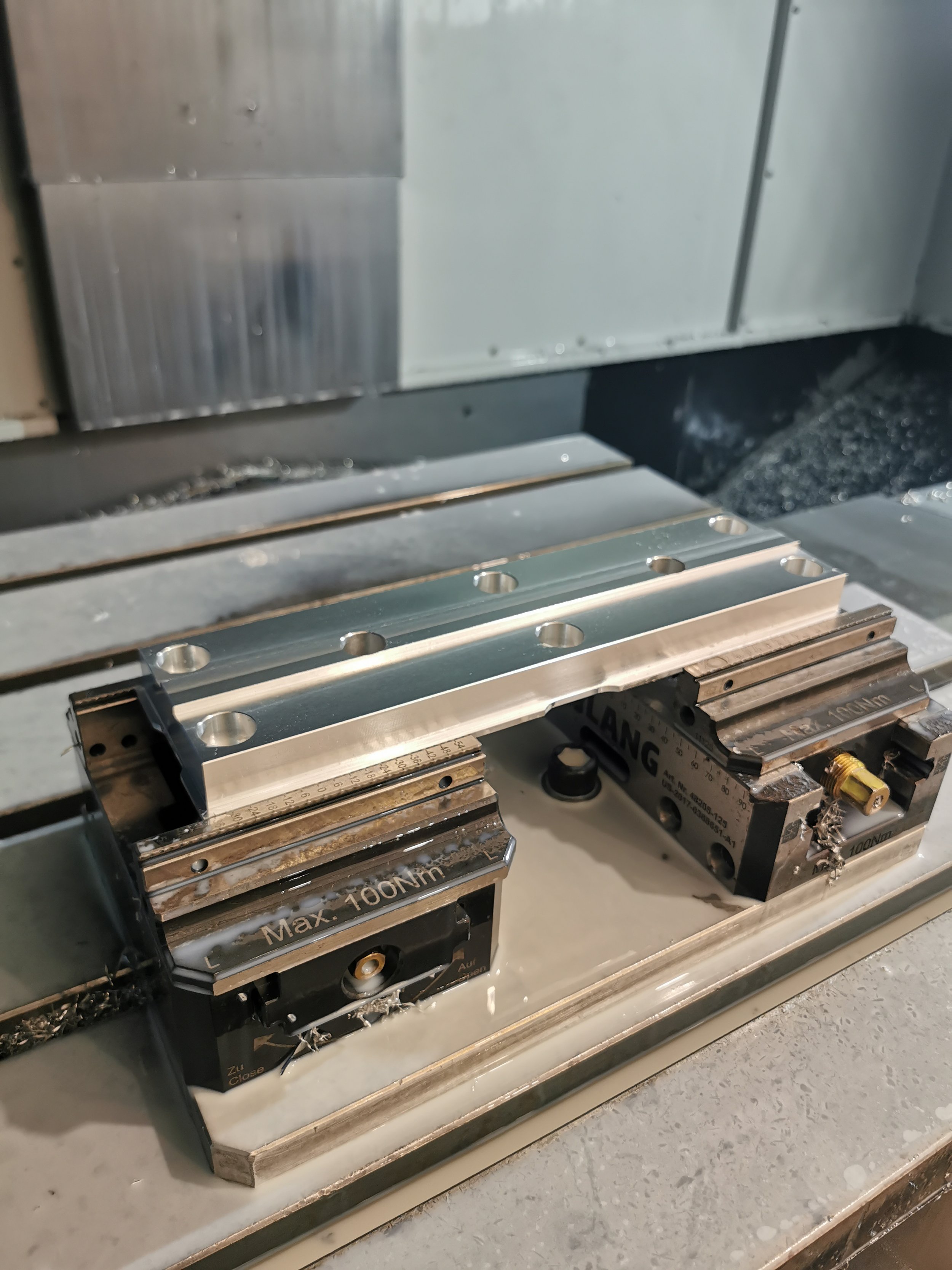 Close-up of metal and plastic machine components, possibly part of a CNC machine or industrial equipment, with measurement markings and fittings.