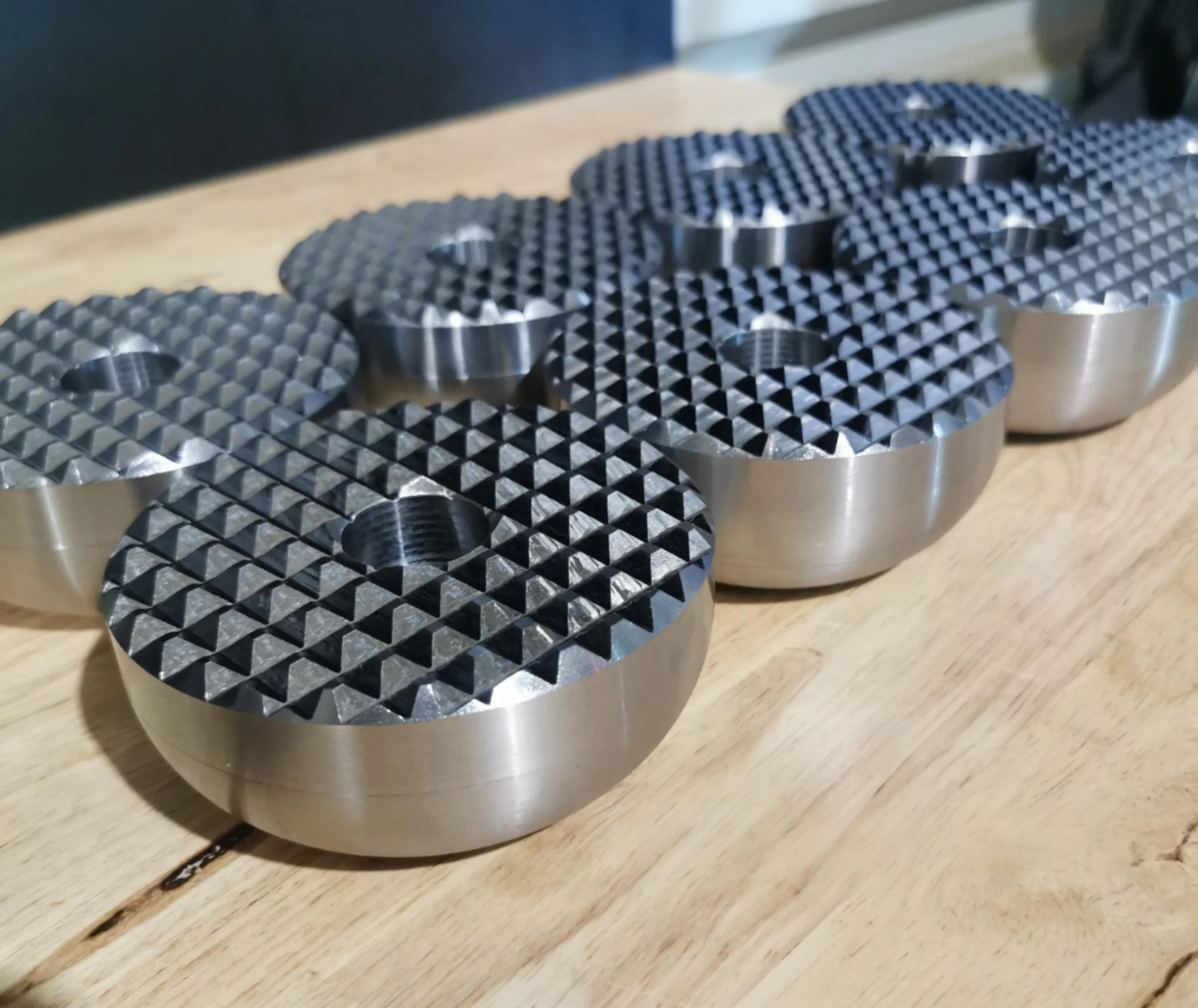 Set of metallic chess pieces with textured tops on a wooden surface.