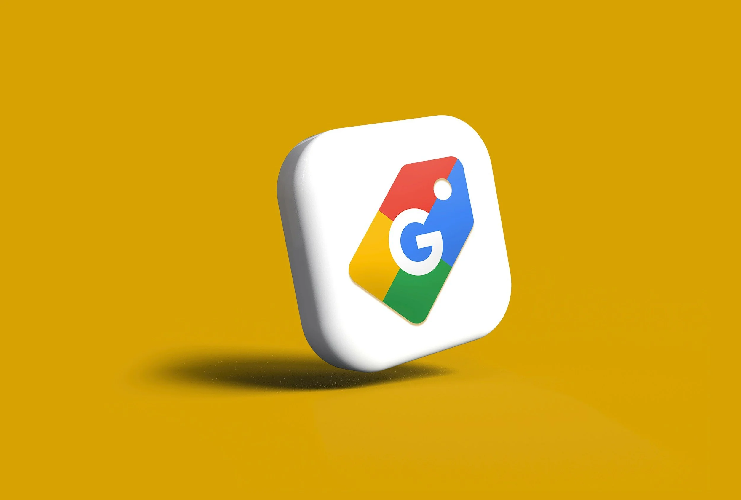 3D illustration of a Google application icon with a colorful 'G' on a white rounded square background, set against a mustard yellow background.