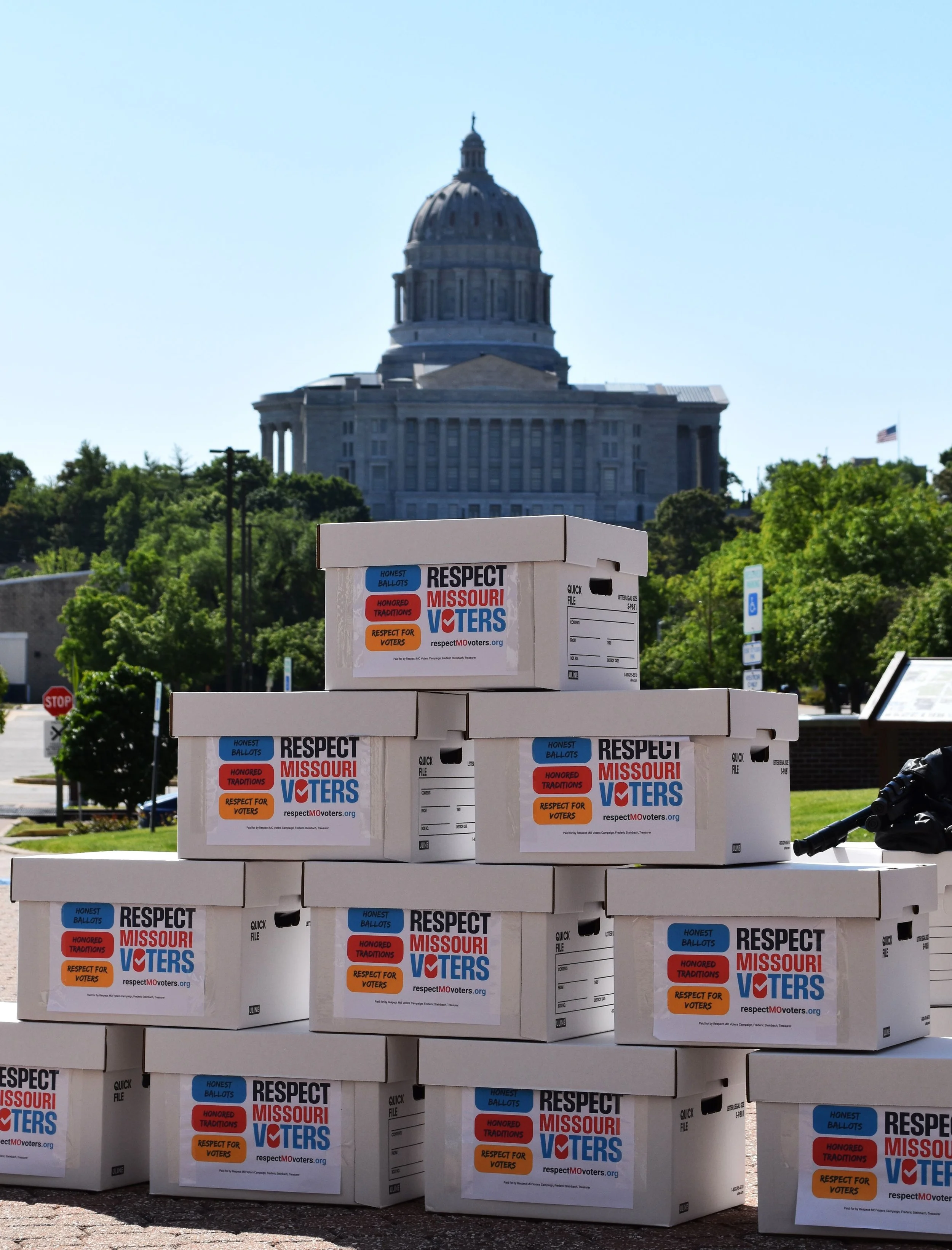 Stacked boxes of signed Respect Missouri Voters' petitions with the Missouri State Capital dome in the background.
