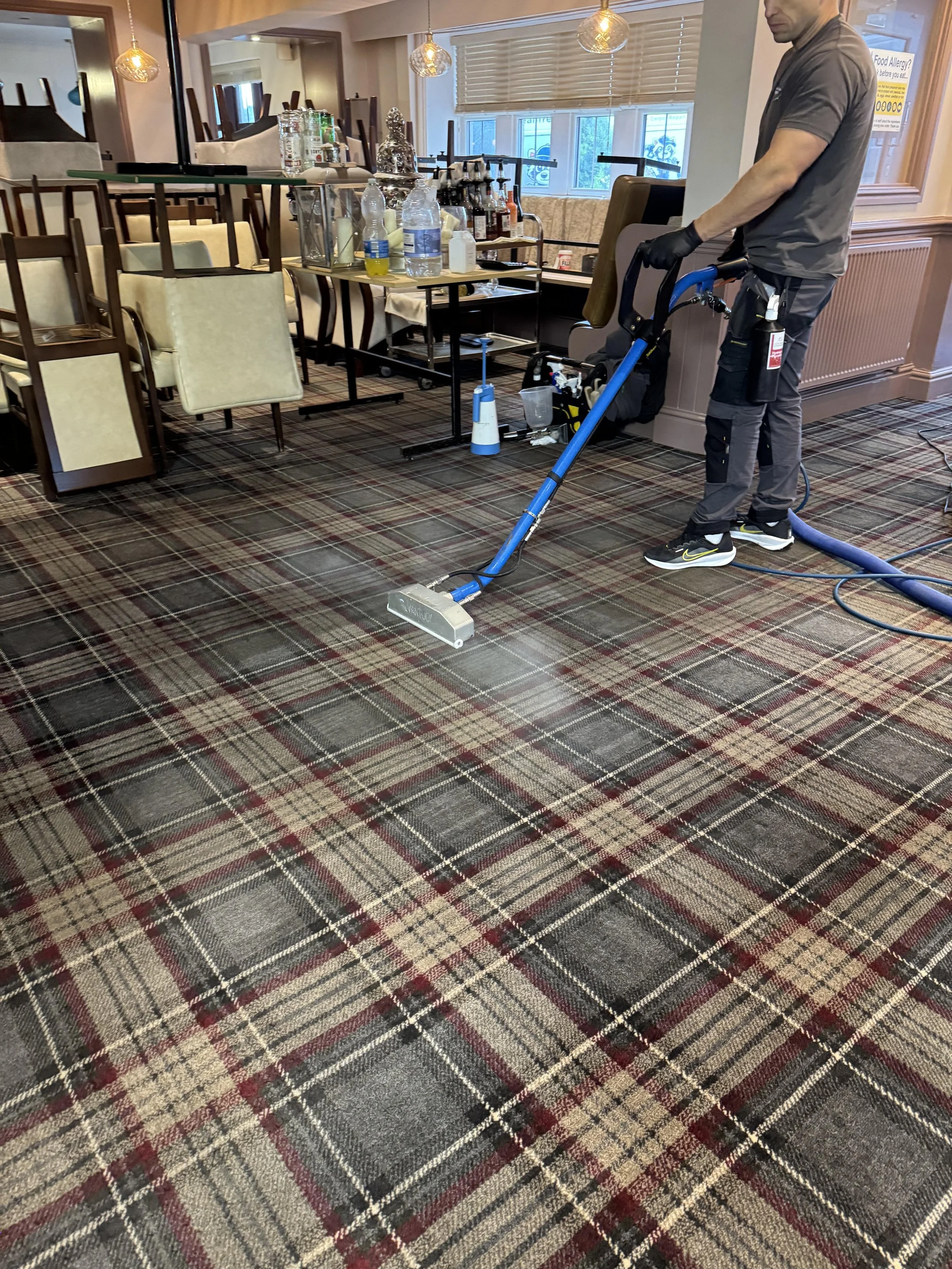 Expert technician commercial carpet cleaning in restaurant with powerful extraction equipment in Preston