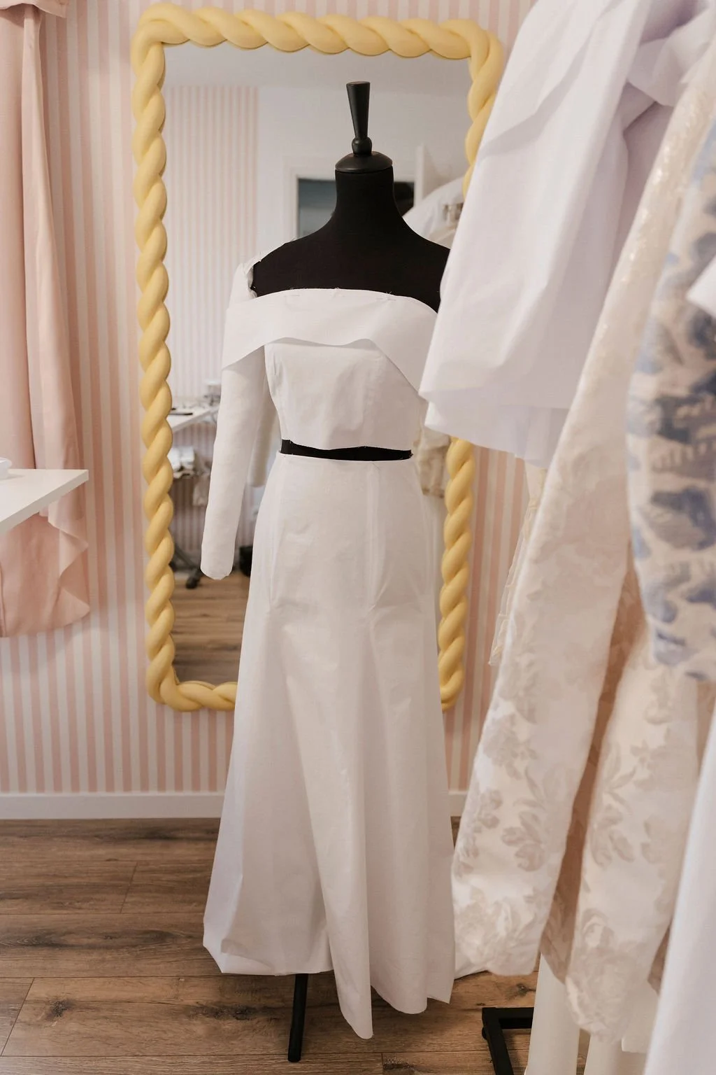 Femme préparant une robe de mariage dans une pièce lumineuse.