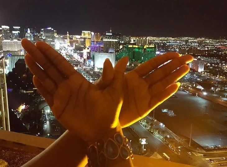 Two hands held up against a city skyline at night, with illuminated buildings and streets in the background.