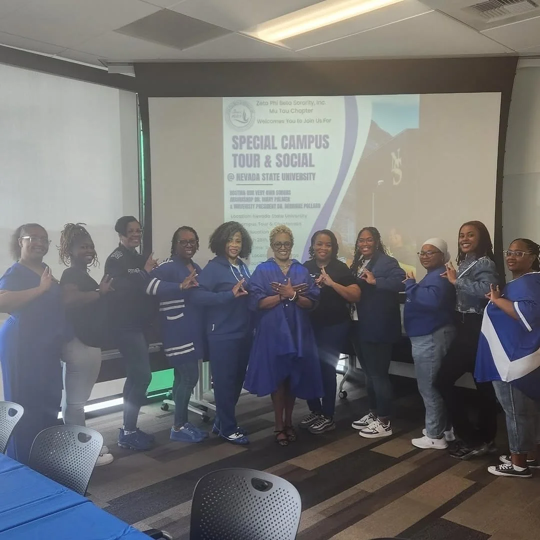 Group of women standing together at Nevada State University during a special campus tour and social event, wearing matching blue and black outfits.