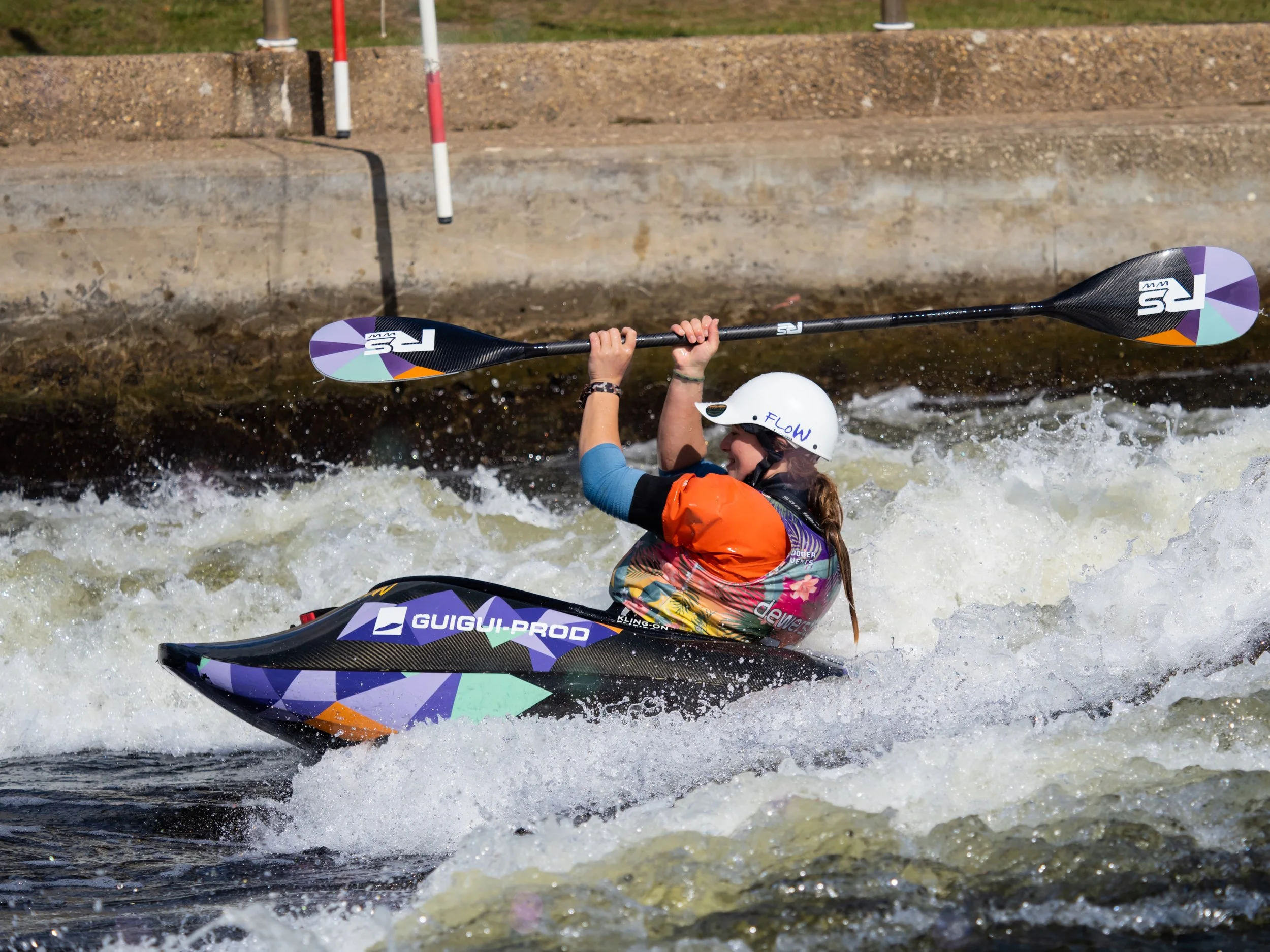 Woman in a freestyle kayak surfing with matching boat and paddle design