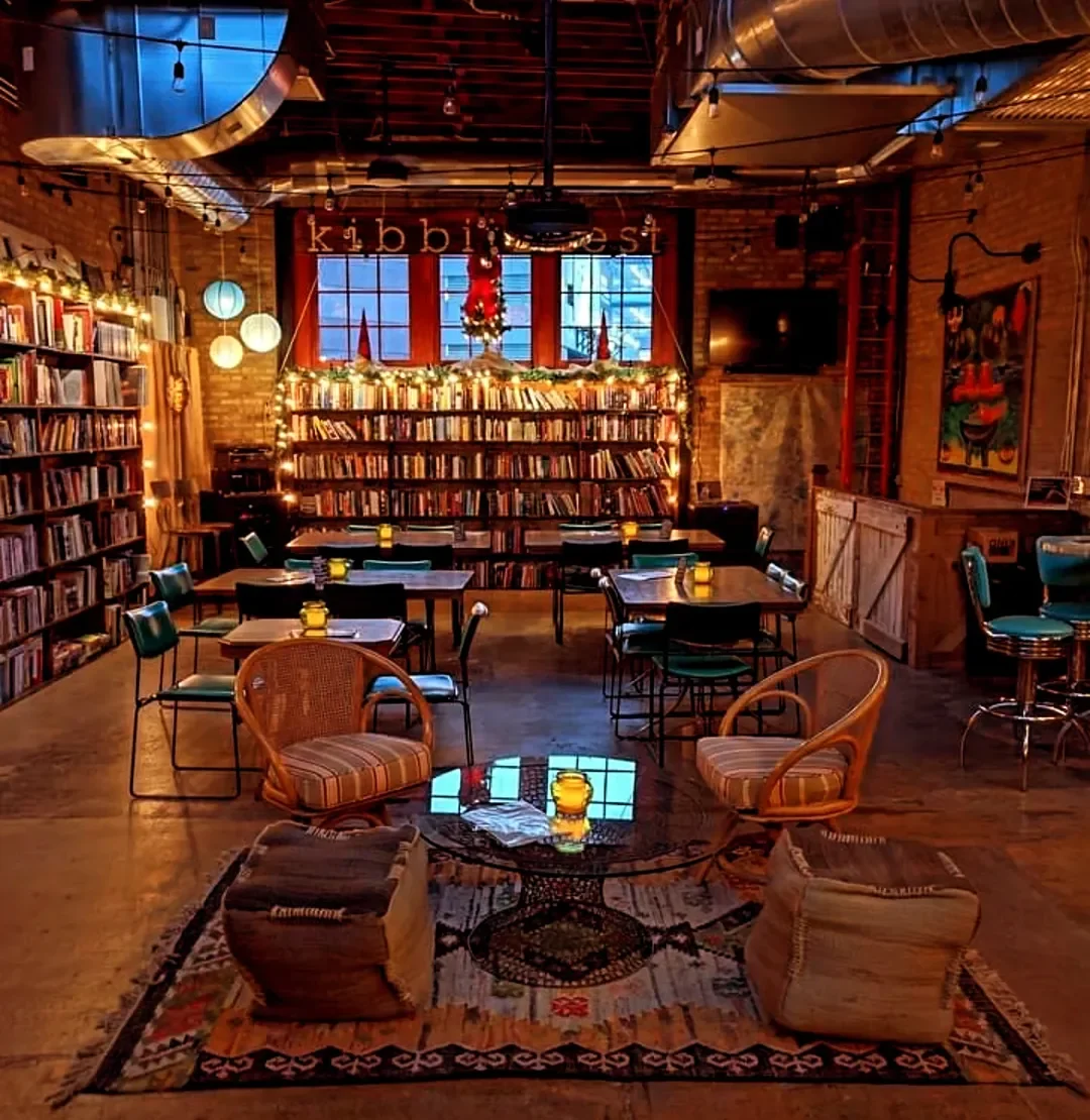 A cozy indoor space decorated for Christmas with bookshelves, tables, and chairs, warm lighting and warm lighting.